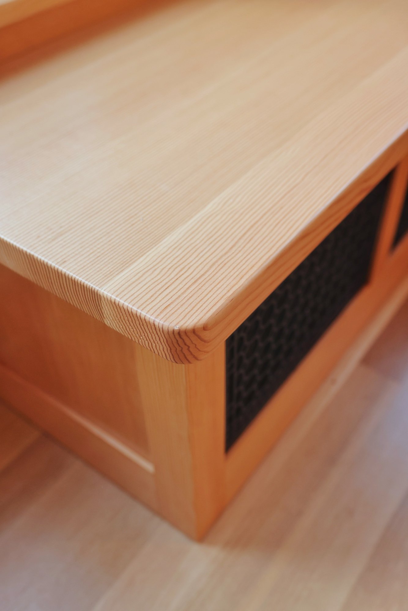 Close-up of a wooden piece of furniture, possibly a cabinet or drawer with a wicker panel on the side.