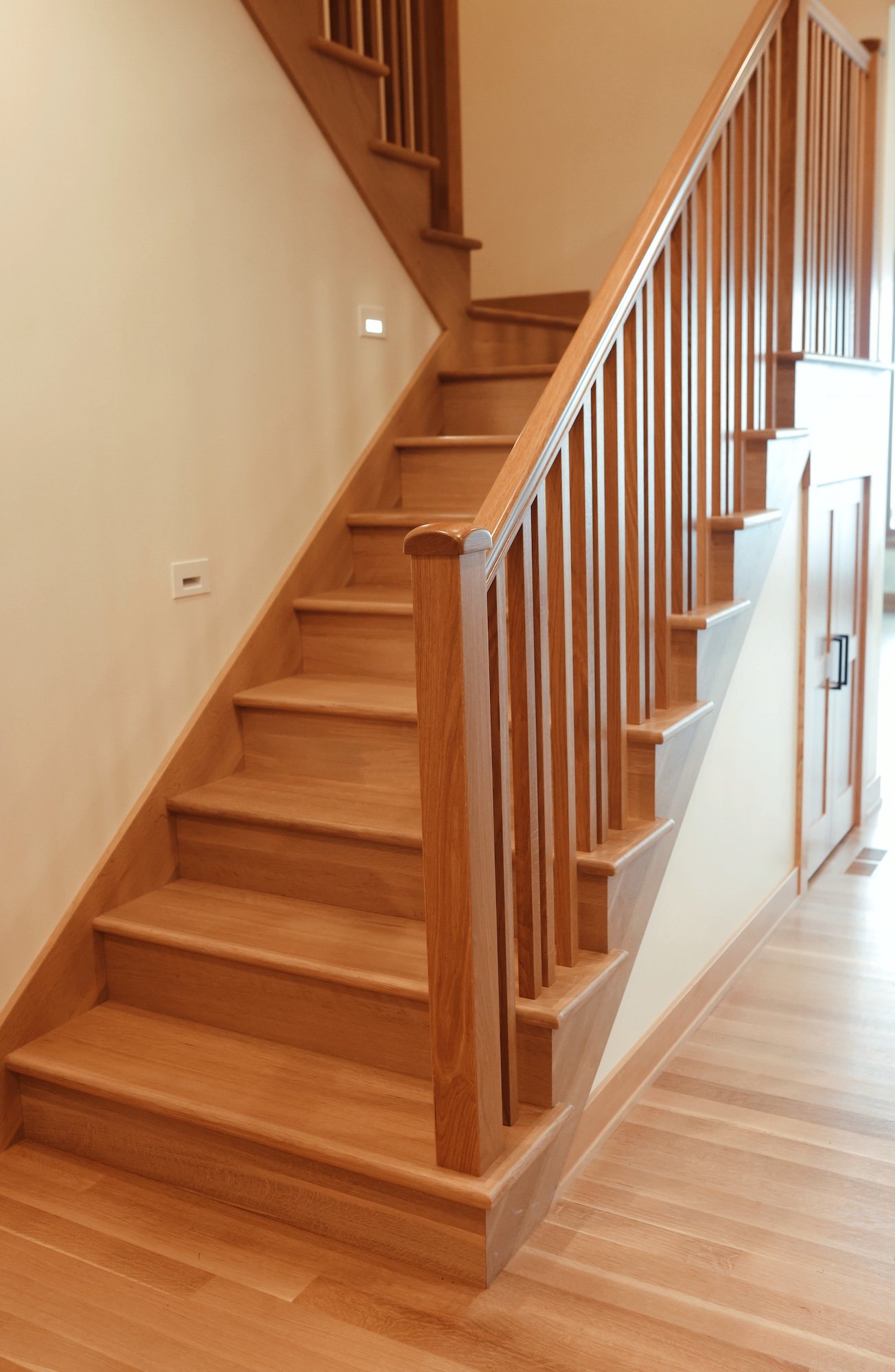 Wooden staircase with beige walls and wood flooring in a home interior.