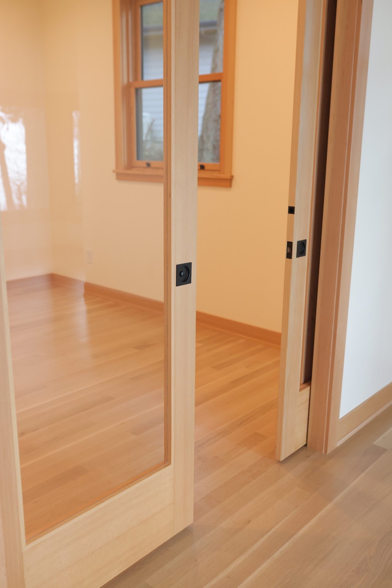 Interior of a house under construction with wooden framing, a door with glass panel, and a window.