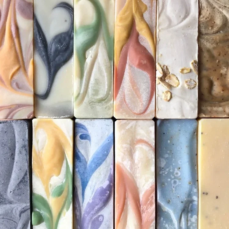 Différents morceaux de savon artisanal avec des motifs colorés et marbrés.