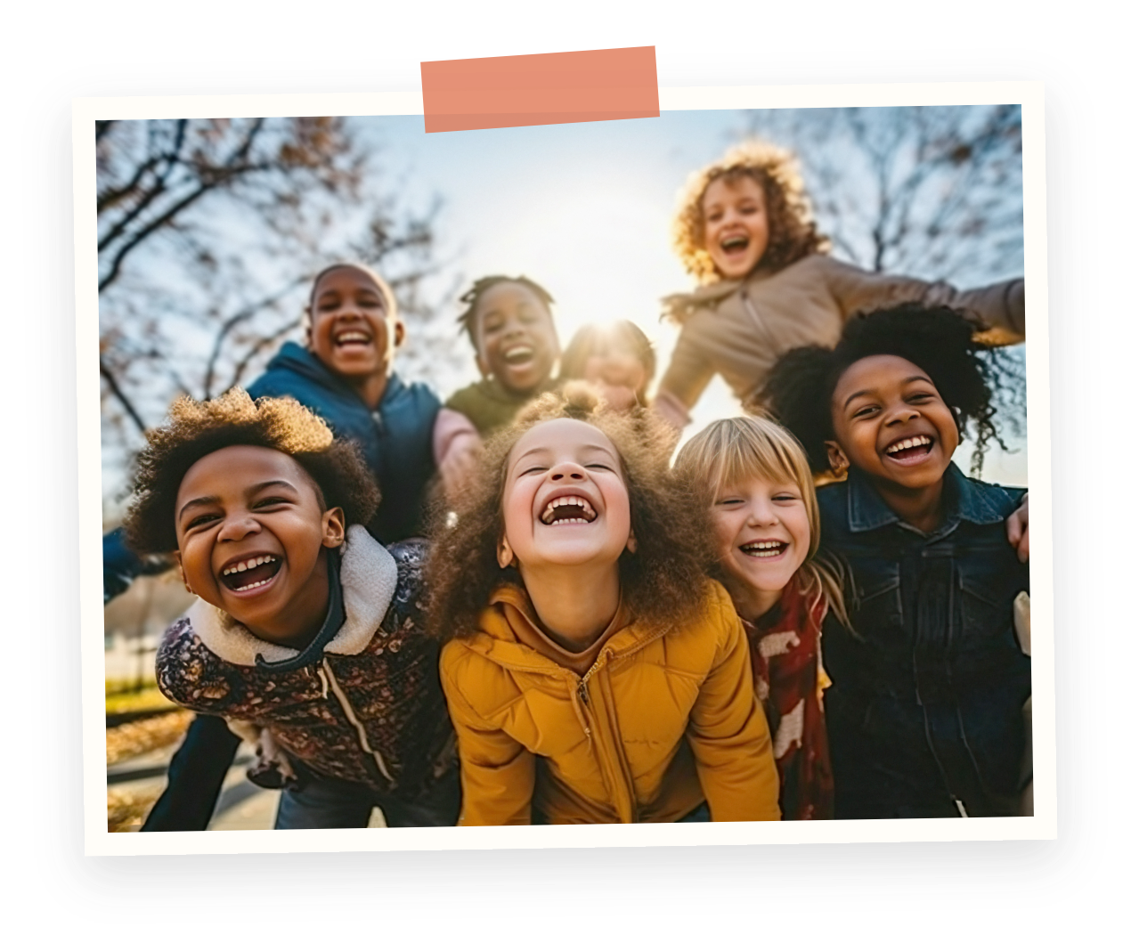 Group of smiling children playing outdoors in fall, photo taken from low angle with sunlight behind