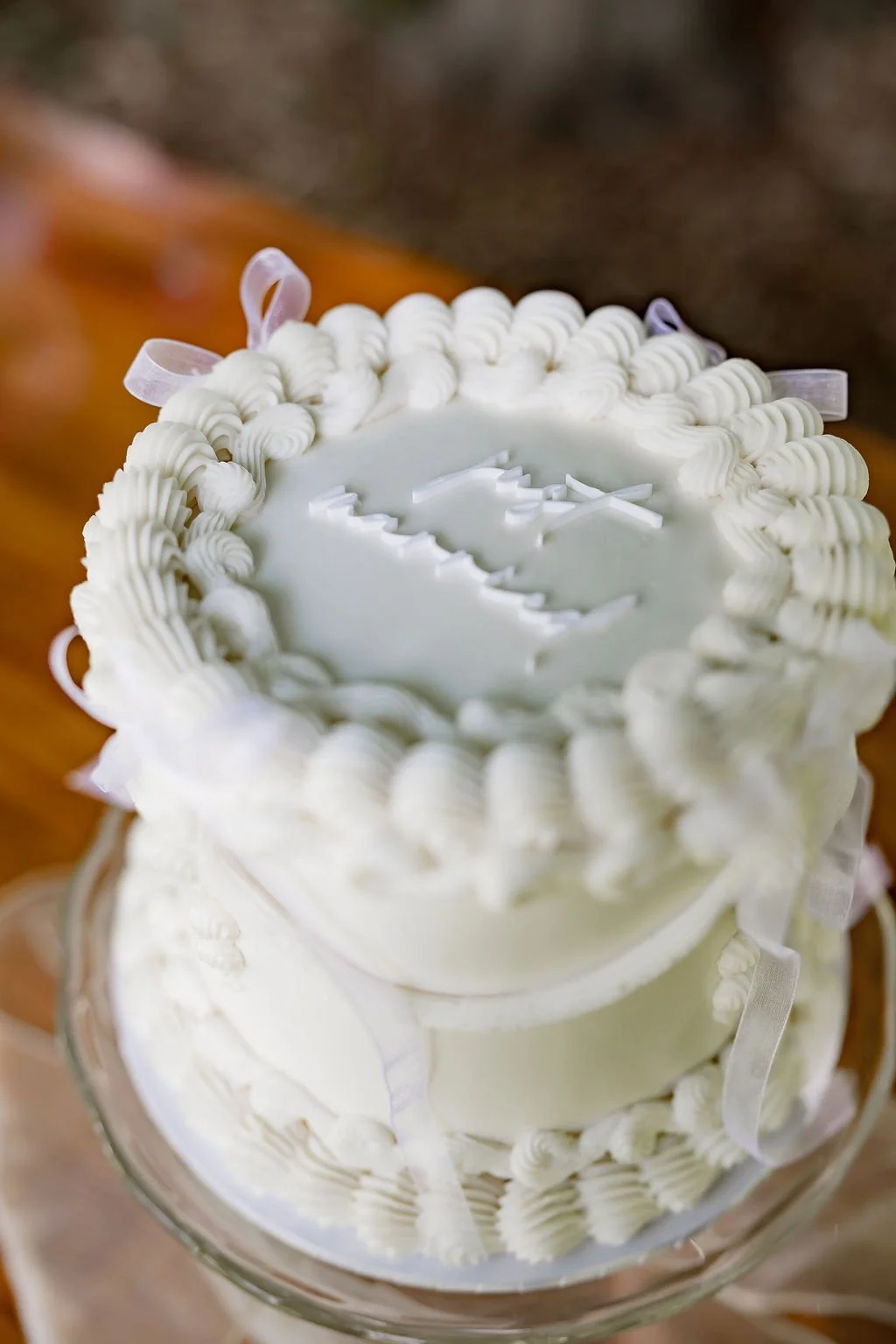 White round cake with decorative piping and a logo on top.
