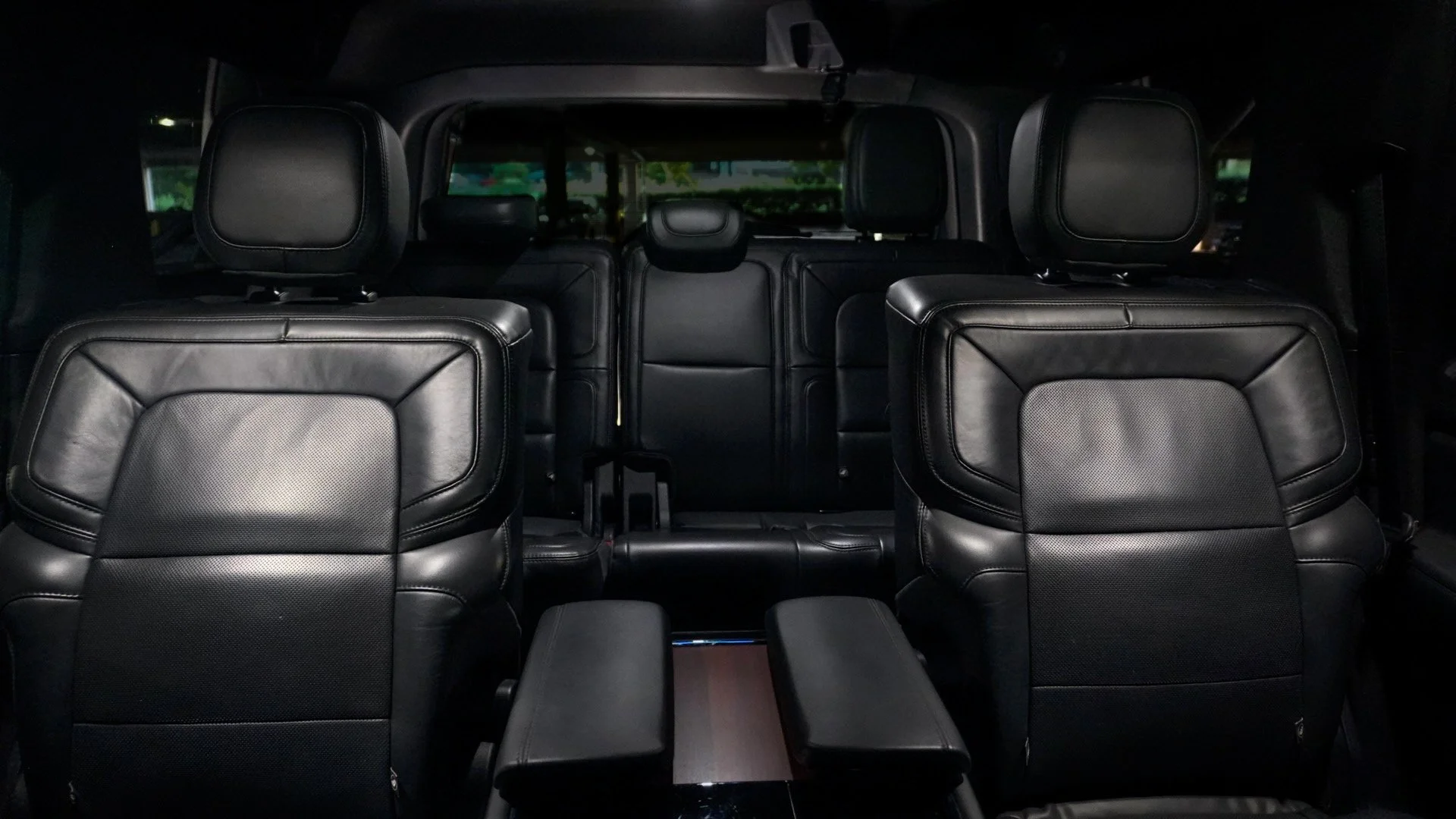 Interior of a vehicle with black leather seats, including front and middle row seats with headrests, viewed from the back seats.