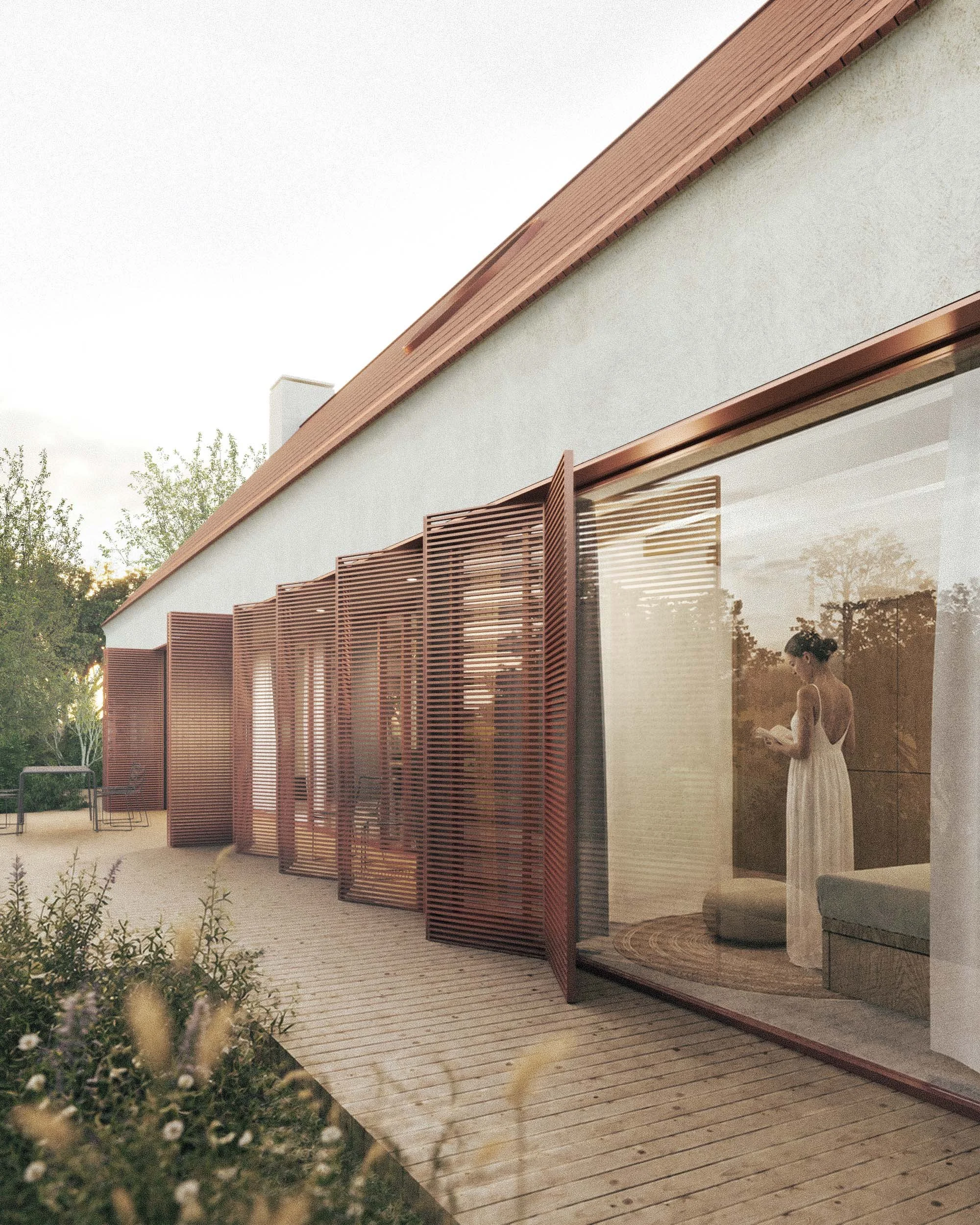 Modern house with red slatted exterior panels, large windows, and a wooden deck, surrounded by greenery, during sunset.