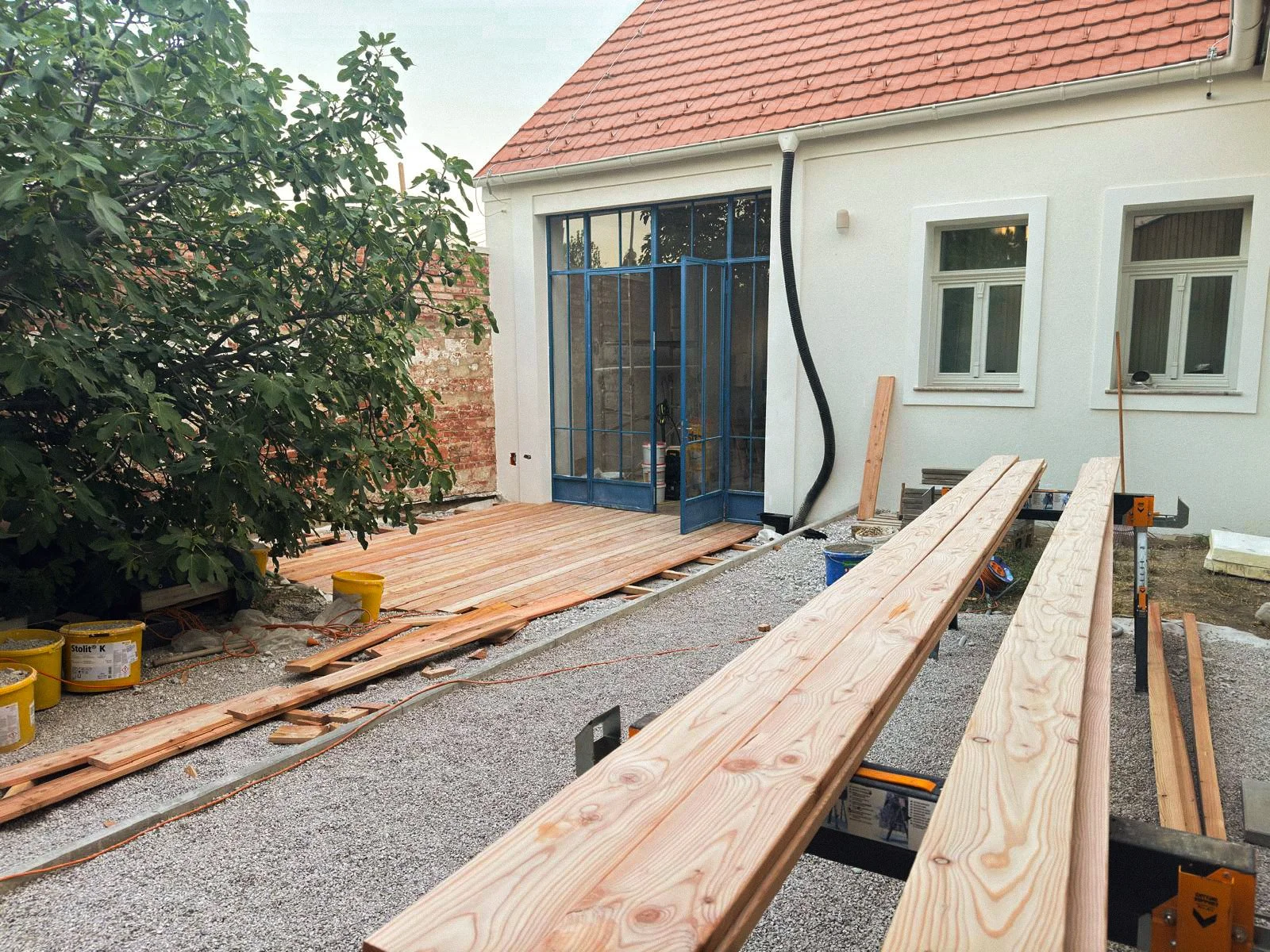 Construction site of a house with wooden deck and building materials.
