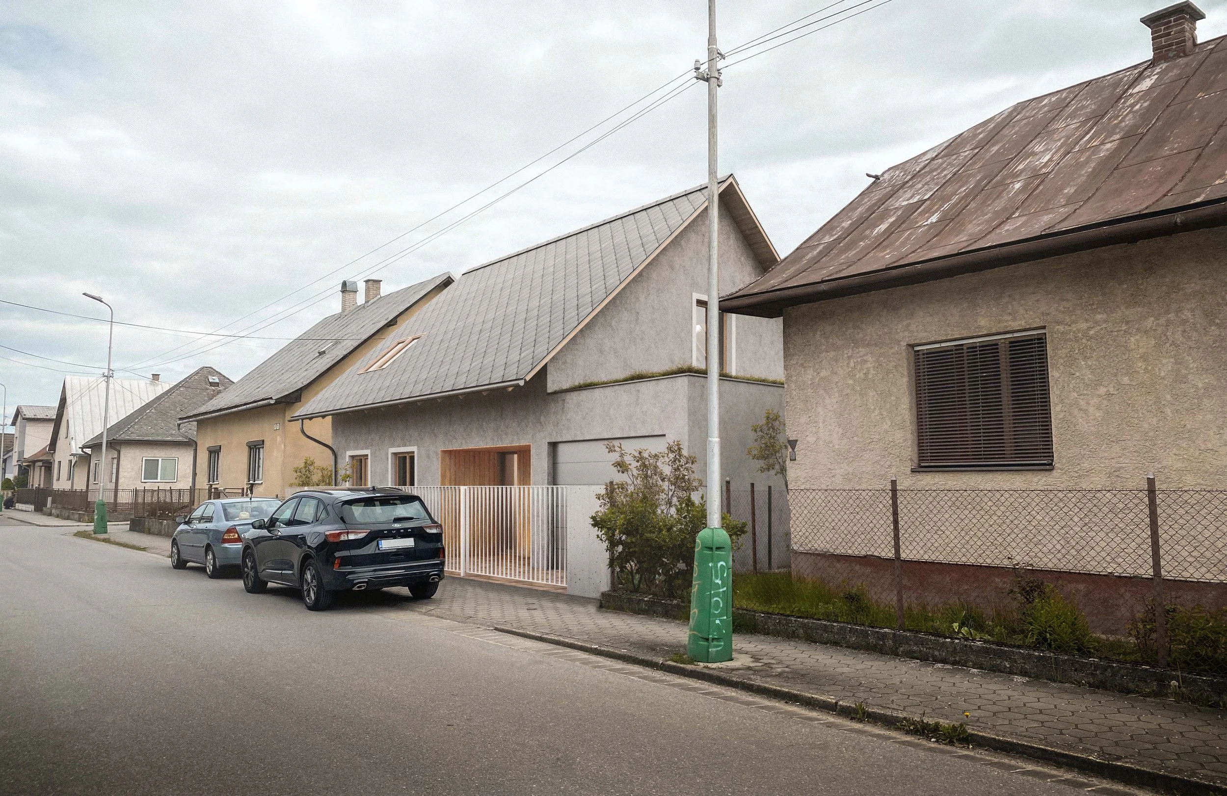 Street view of residential houses with modern roofing, parked cars, a streetlamp, and utility poles under cloudy sky.