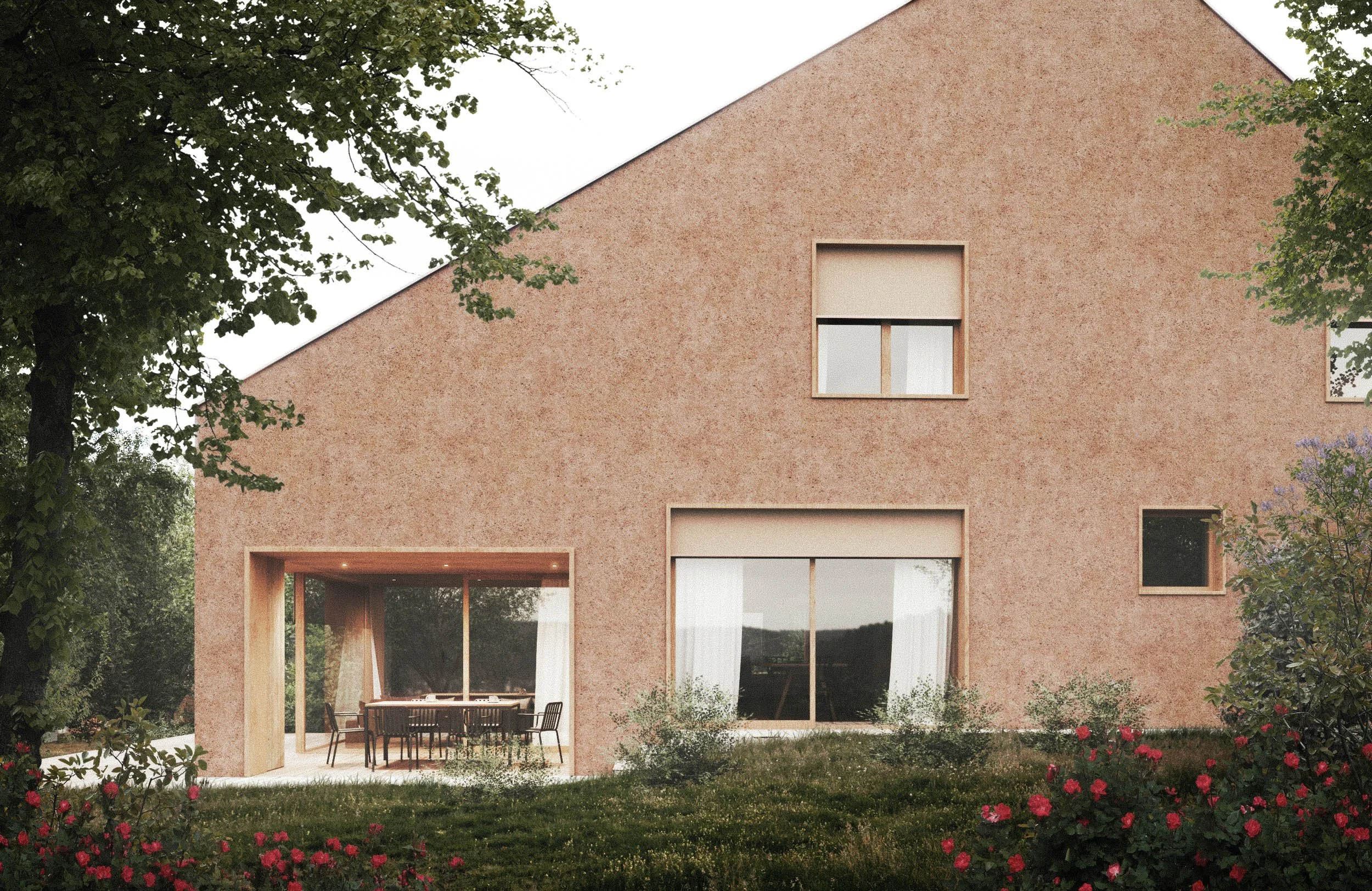 A modern house with a pink textured facade, large floor-to-ceiling windows, and a wooden outdoor dining area. The house is surrounded by greenery, including trees and blooming pink flowers.