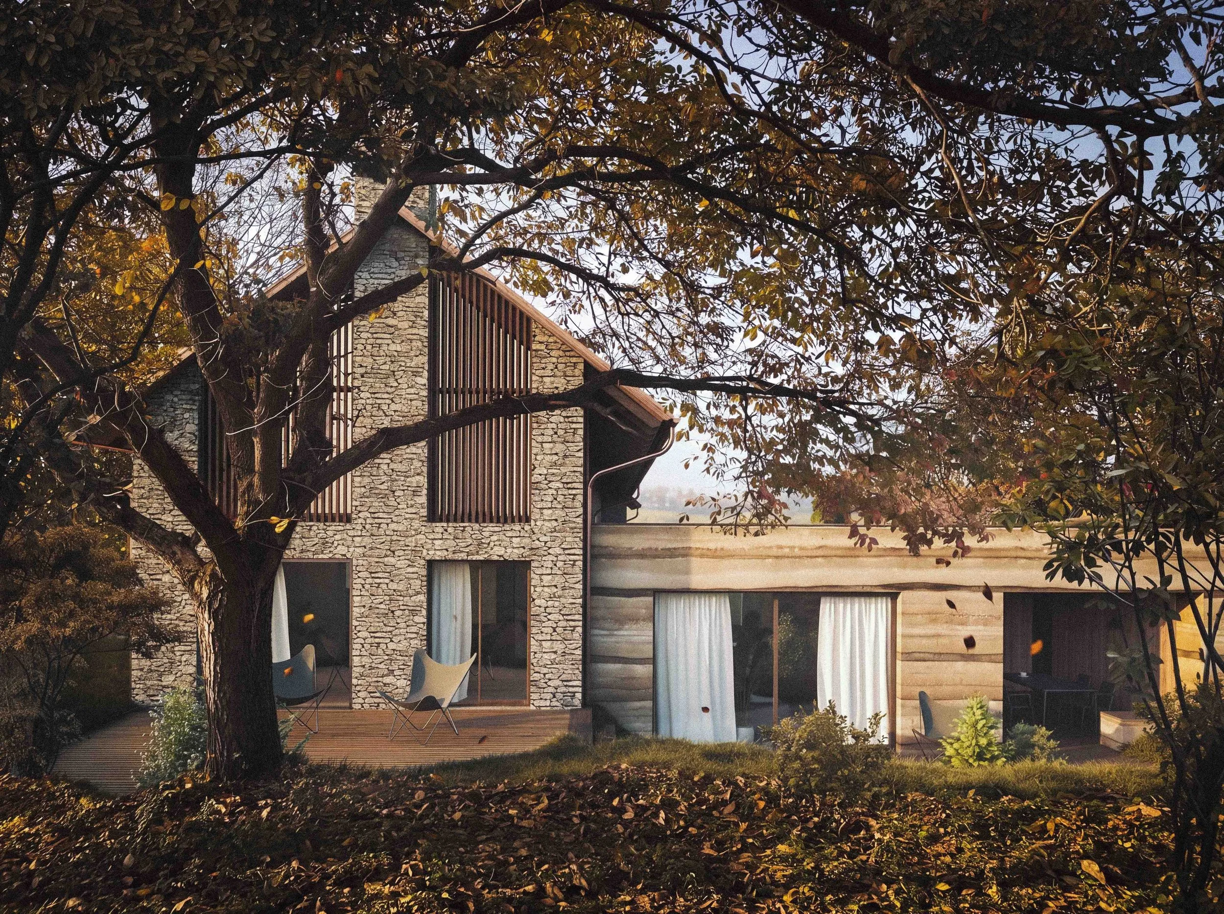 A house with stone walls and wooden elements, viewed through branches and leaves of trees, with some outdoor furniture in the yard.