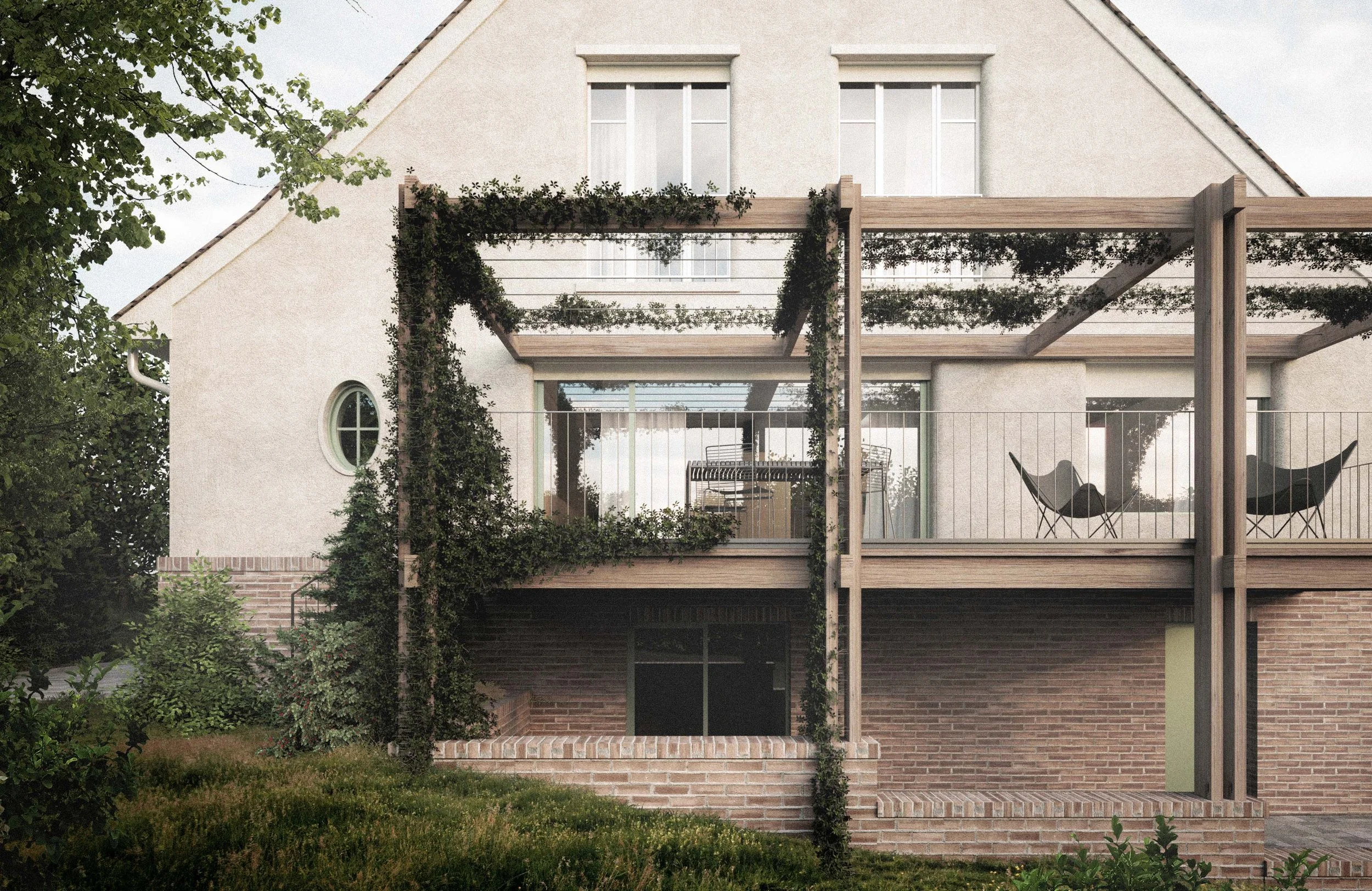 Two-story house with a brick lower level, white upper walls, and a gabled roof. The house features large windows and a wooden balcony with a pergola, some greenery, and outdoor chairs visible on the balcony.