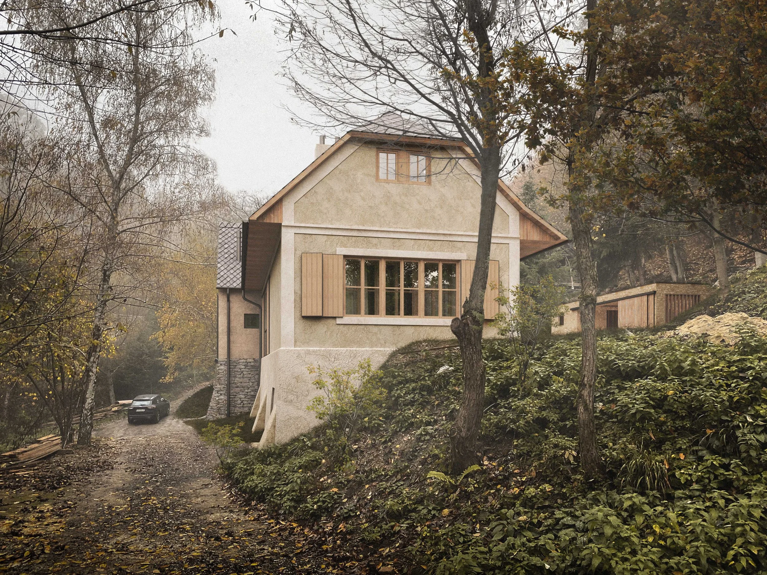 A modern house on a hillside surrounded by trees with autumn foliage, with a dirt driveway and two cars parked.