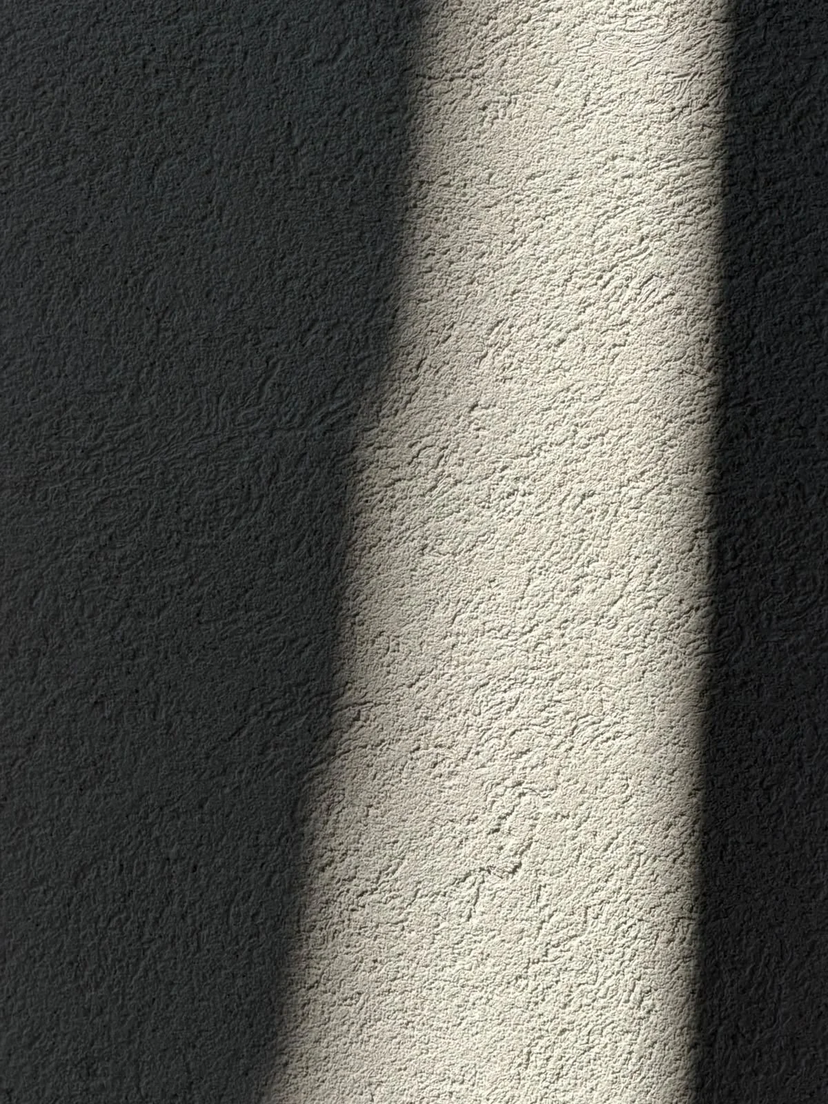 Shadows cast on a textured wall with a vertical piece of sunlight in the center.