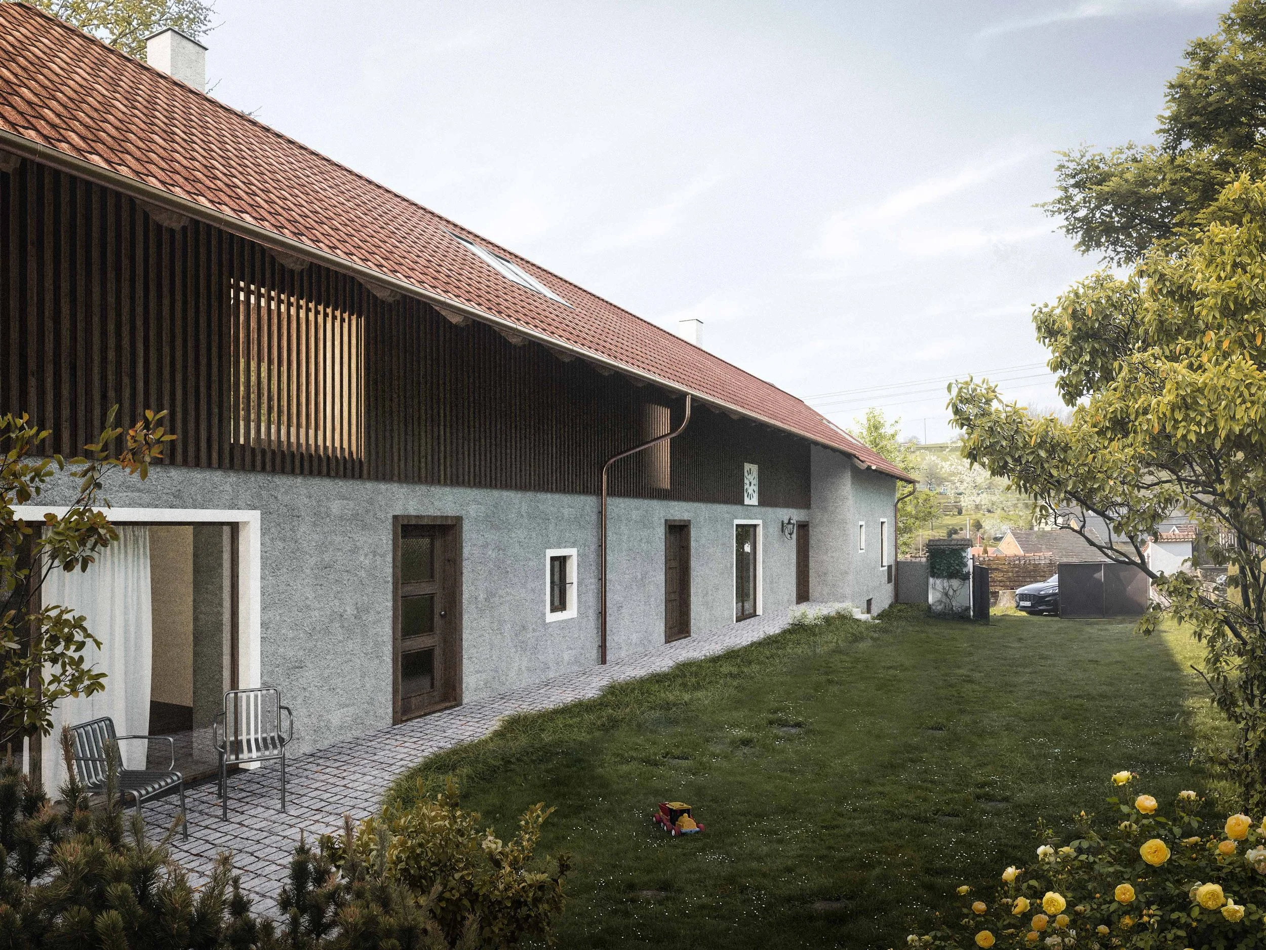 Residential house with red tiled roof, skylights, and wooden balcony, surrounded by a lawn with garden chairs, trees, and flowers.