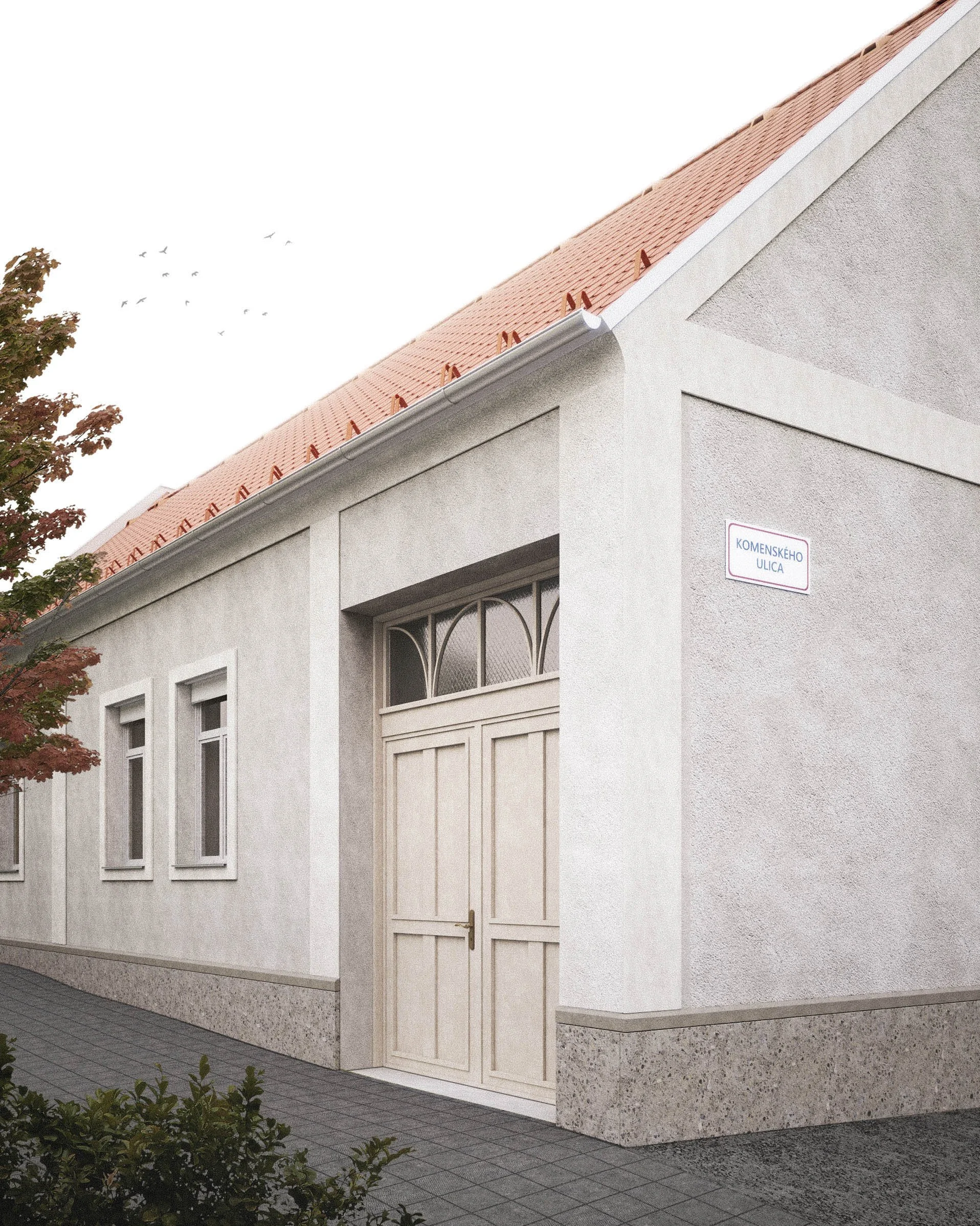 The image shows a section of a white building with an orange tiled roof, on which bird silhouettes are visible in the sky. There is a tree with red leaves on the left side of the image, and a sign on the building's corner reads 'KOMENSKÉHO ULICA'. The building has several windows with decorative metal bars, and the sidewalk in front is paved with gray tiles.