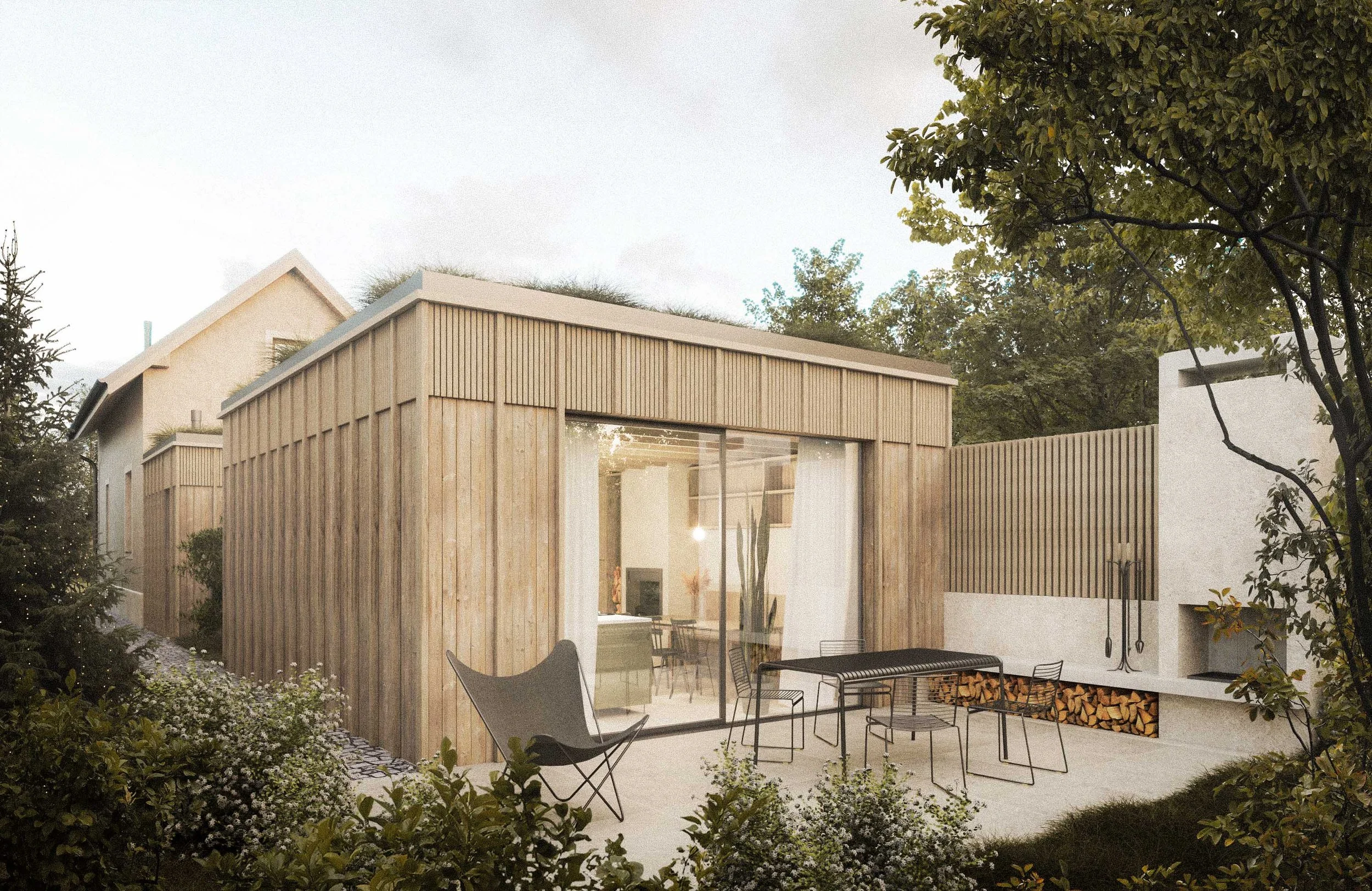 Modern house with wooden exterior panels and large glass windows, patio area with chairs and a fire pit, wood storage, surrounded by trees and landscaping.