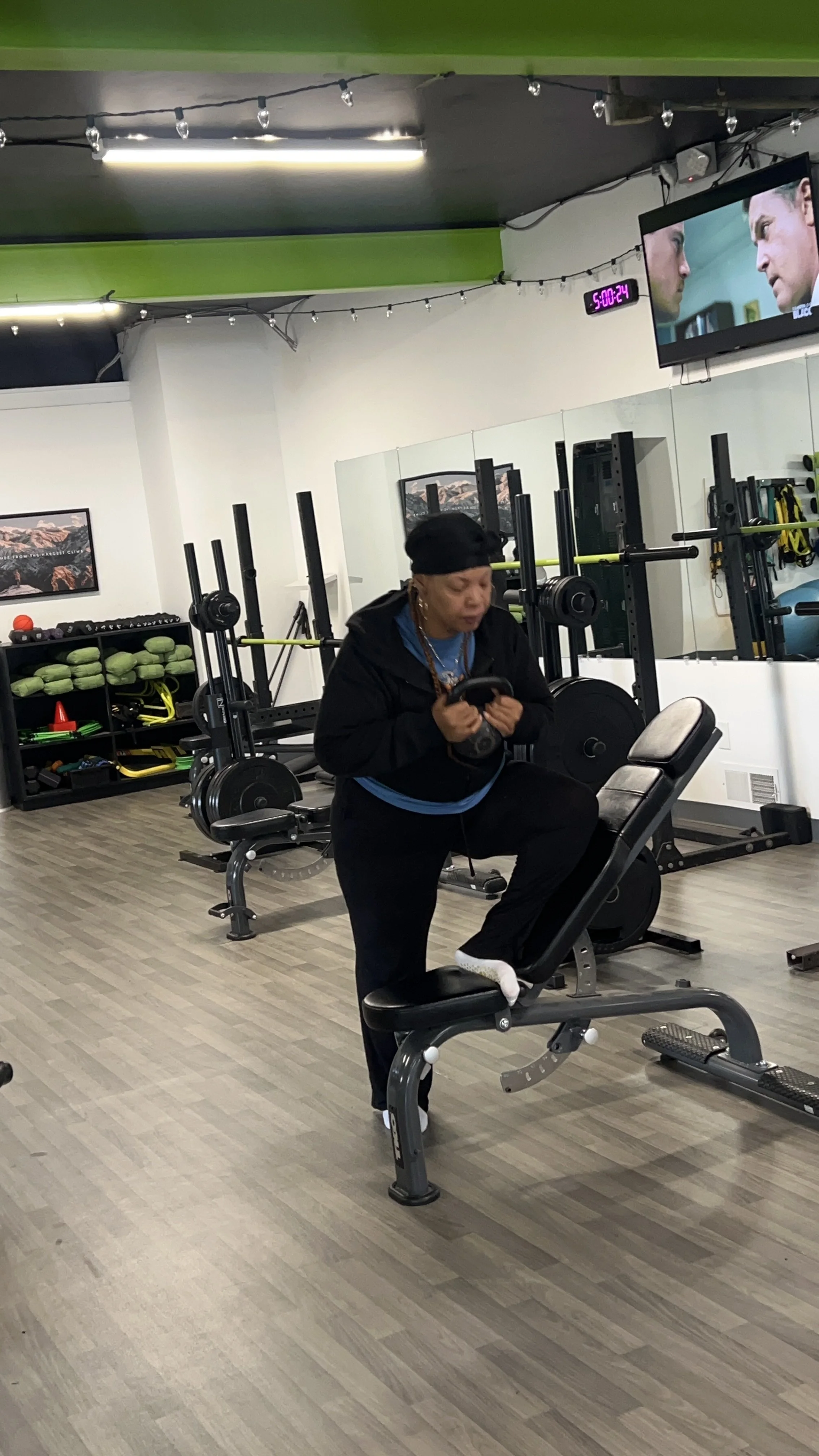 A woman working out on a treadmill in a gym, surrounded by exercise equipment and a large mirror on the wall.