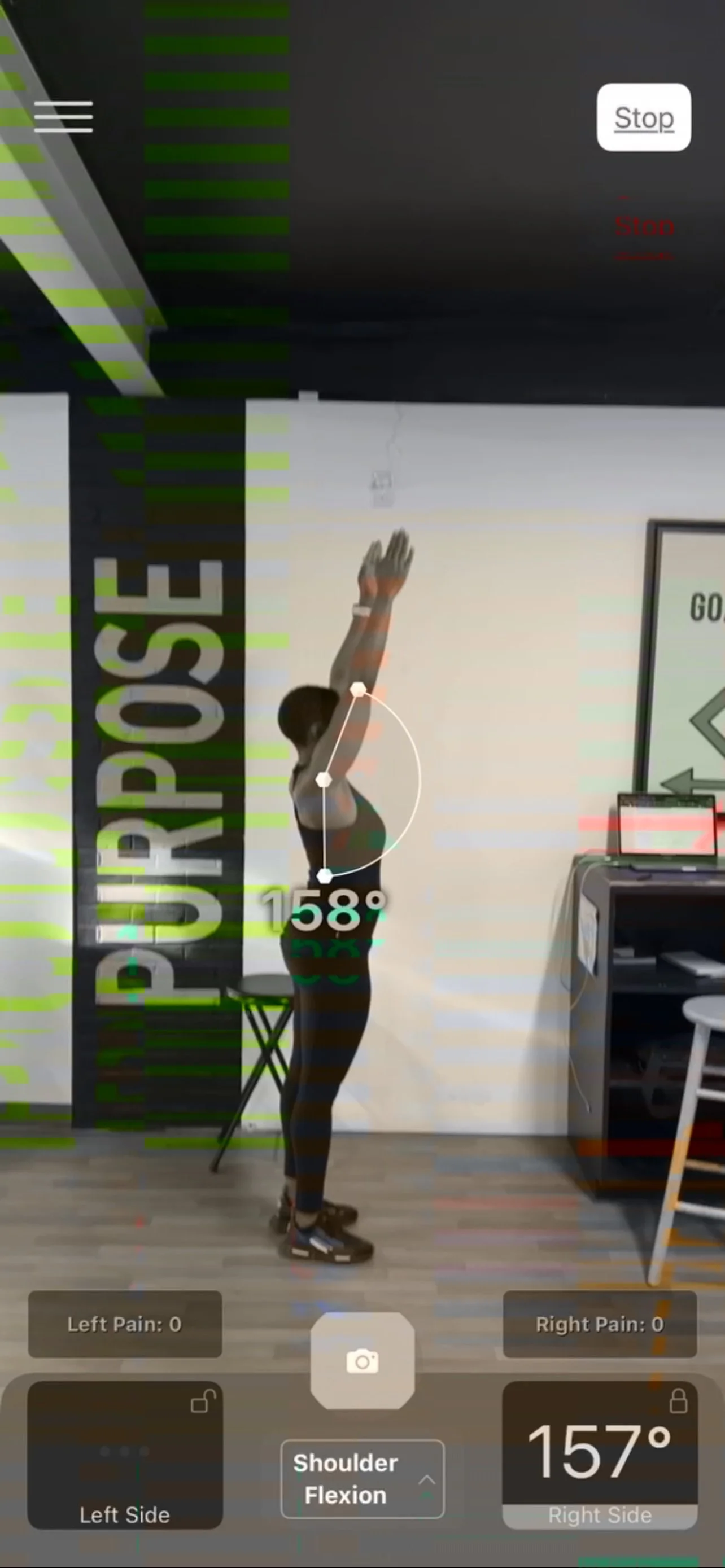 A person performing a shoulder flexion exercise with arms raised overhead, recorded in a digital posture analysis app showing shoulder angle of 158 degrees and body alignment details.