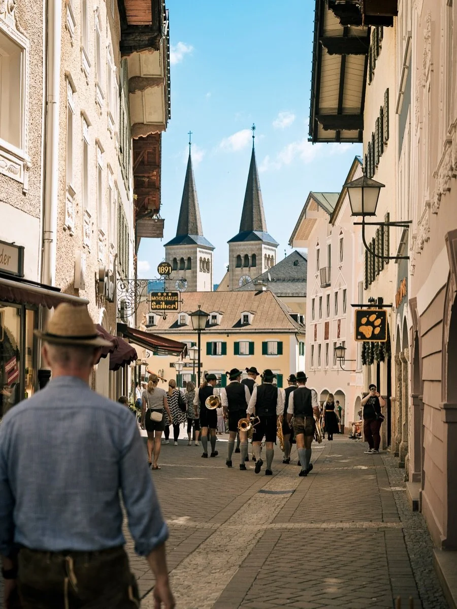 Berchtesgaden, through my lens 📸

One morning, one town. A brass band moving through a narrow lane, a beer wagon rolling toward the Marktplatz, an old painted Gasthaus caught in a shop window across the street, and the mountains sitting behind all o