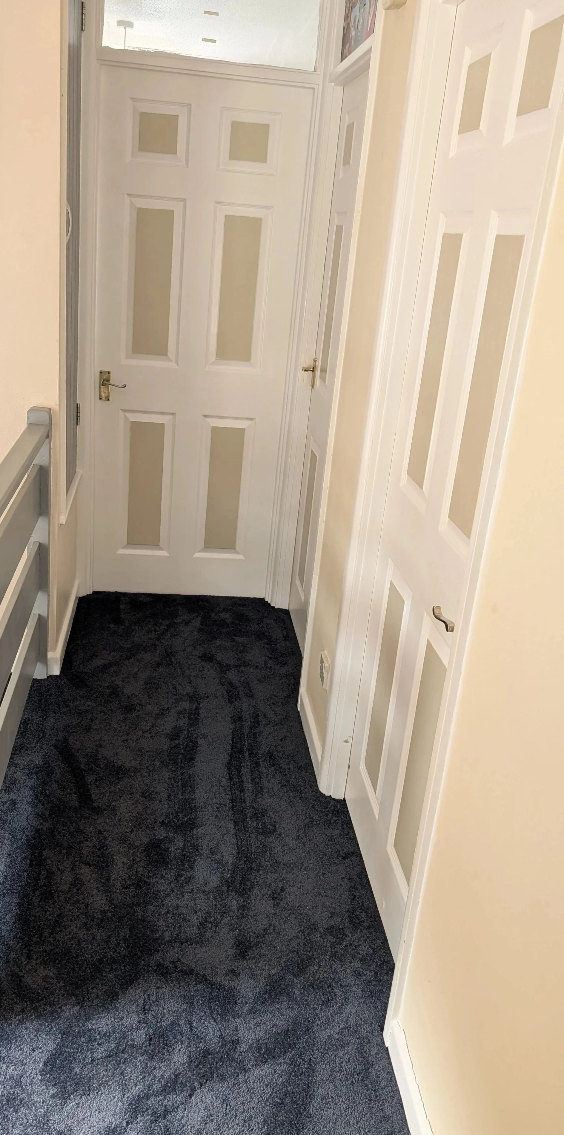 Decorated hallway, doors and fitted a dark carpeted floor.