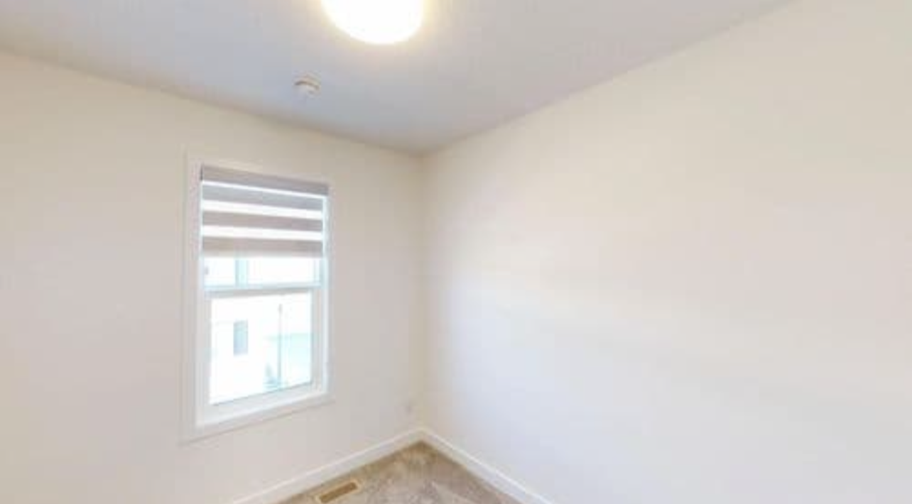 Empty room with white walls, a window with a new blind, and a ceiling light