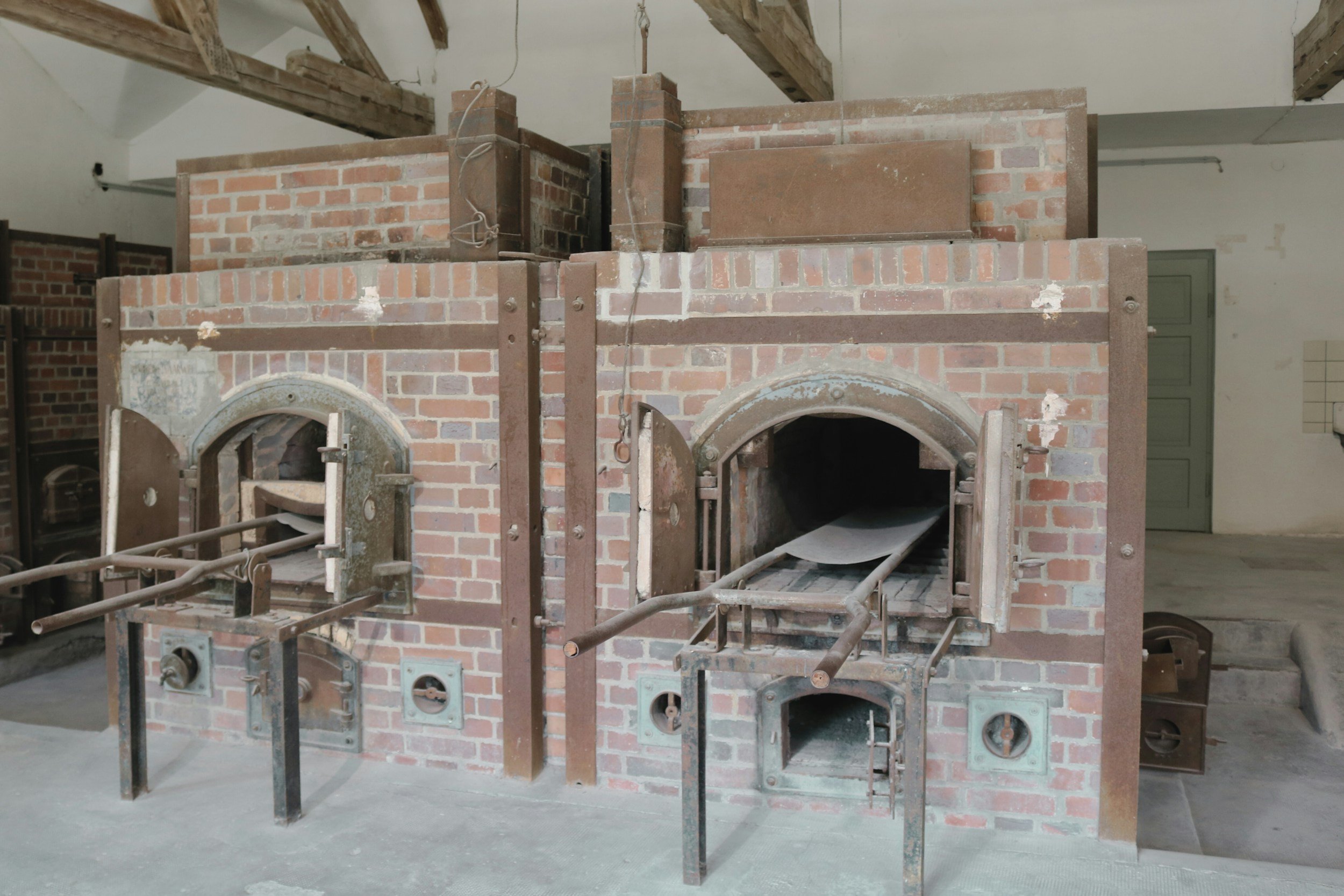 A fireplace under construction made of red bricks with metal framing and a wooden beam overhead.