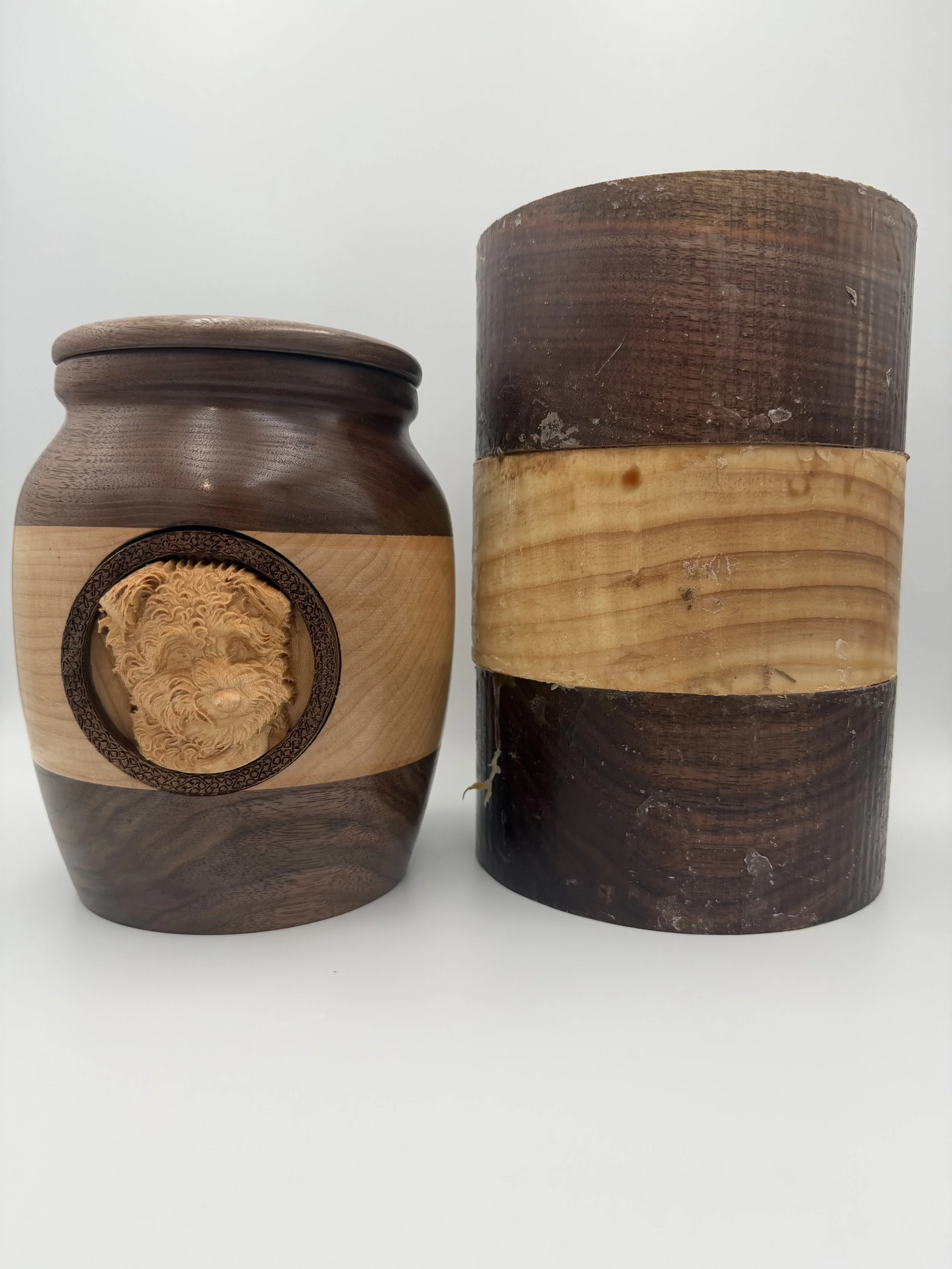 A small wooden container with a circular carved design on the front, next to a larger wooden piece with a layered appearance against a plain white background.
