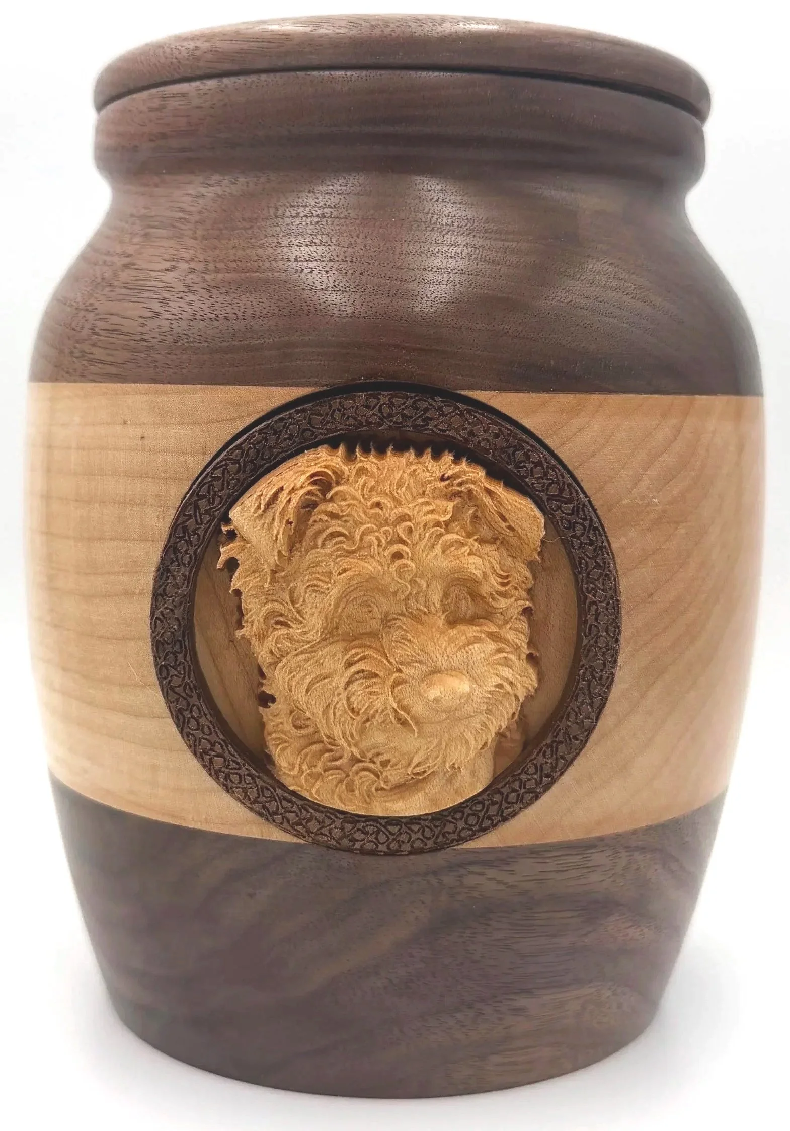 A wooden urn with a decorative circular inlay on its front, showing a detailed, textured, light-colored wood carving inside the inlay.