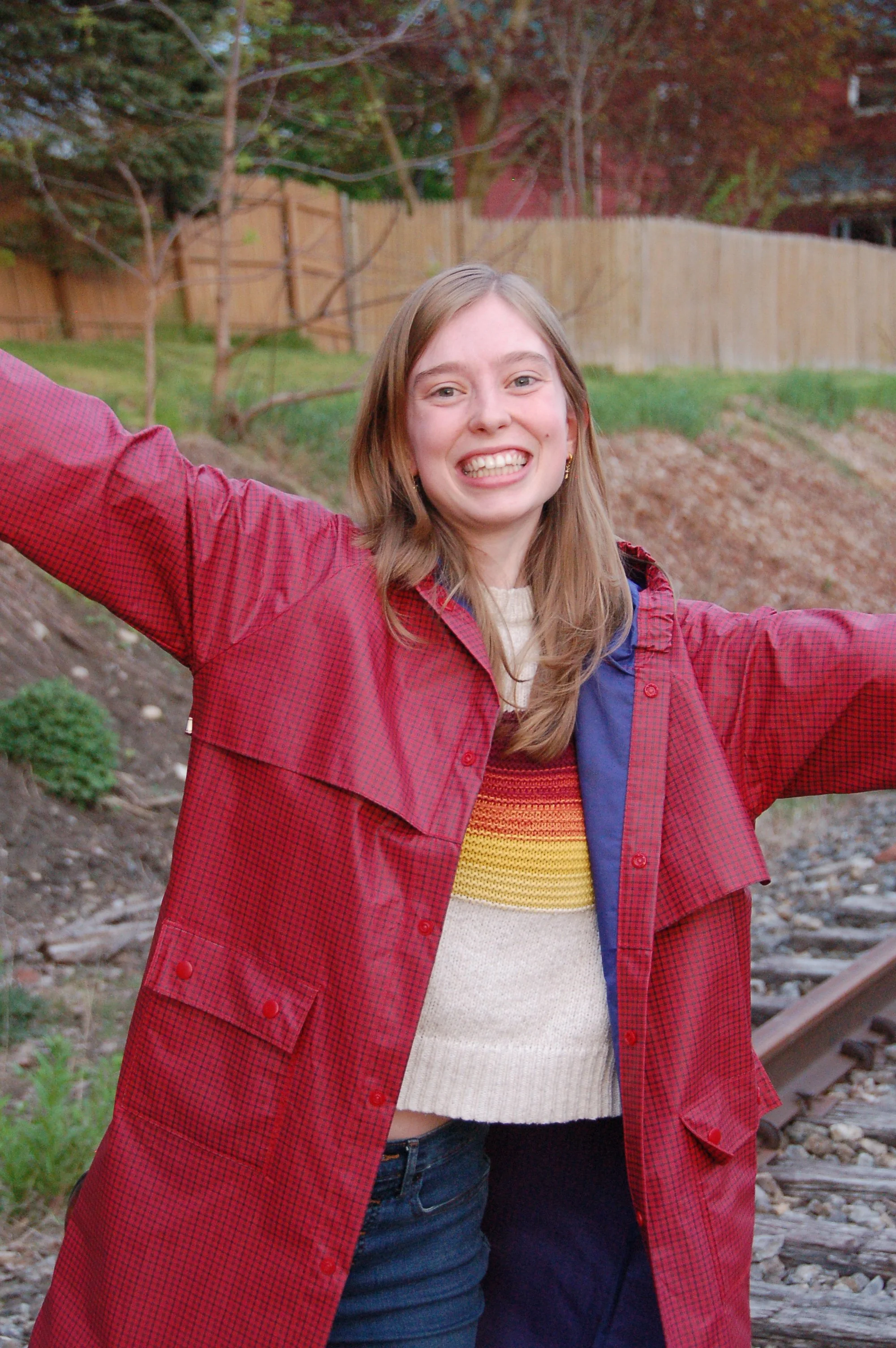 A smiling blonde woman in a red raincoat