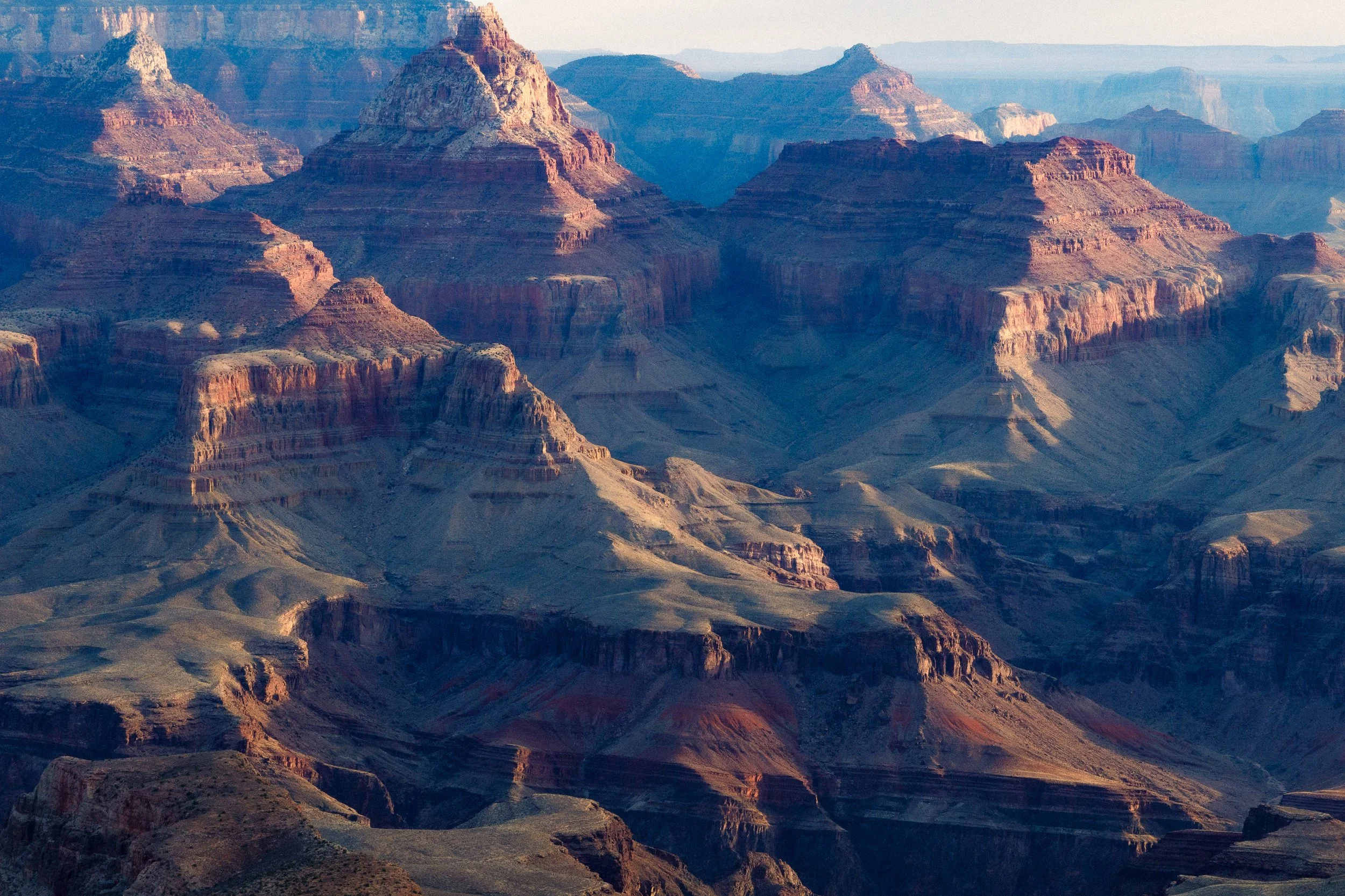 Aerial view of the Grand Canyon displaying layered rock formations and deep valleys with subdued lighting.