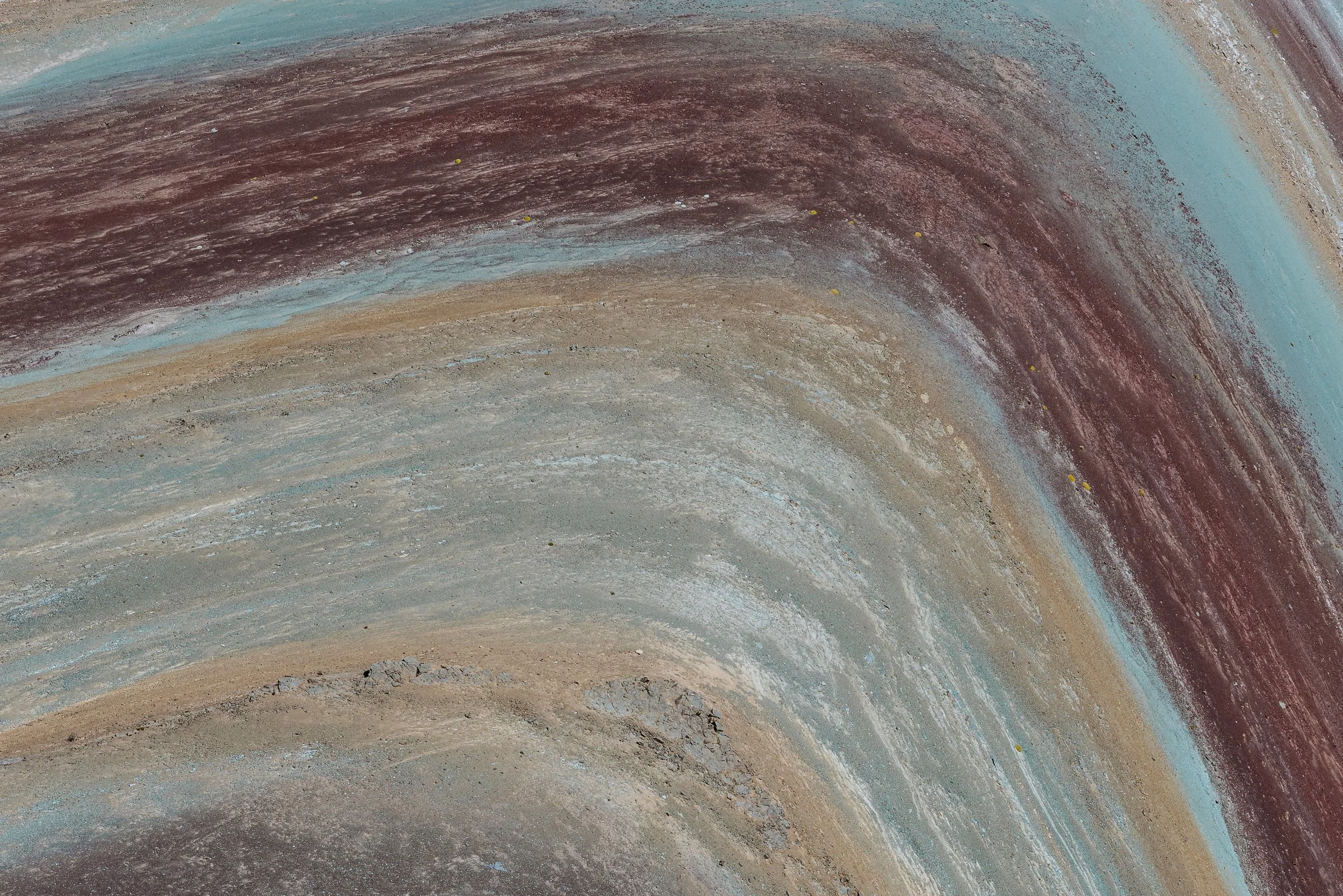Colorful, abstract landscape with curved layers of brown, blue, and beige tones.