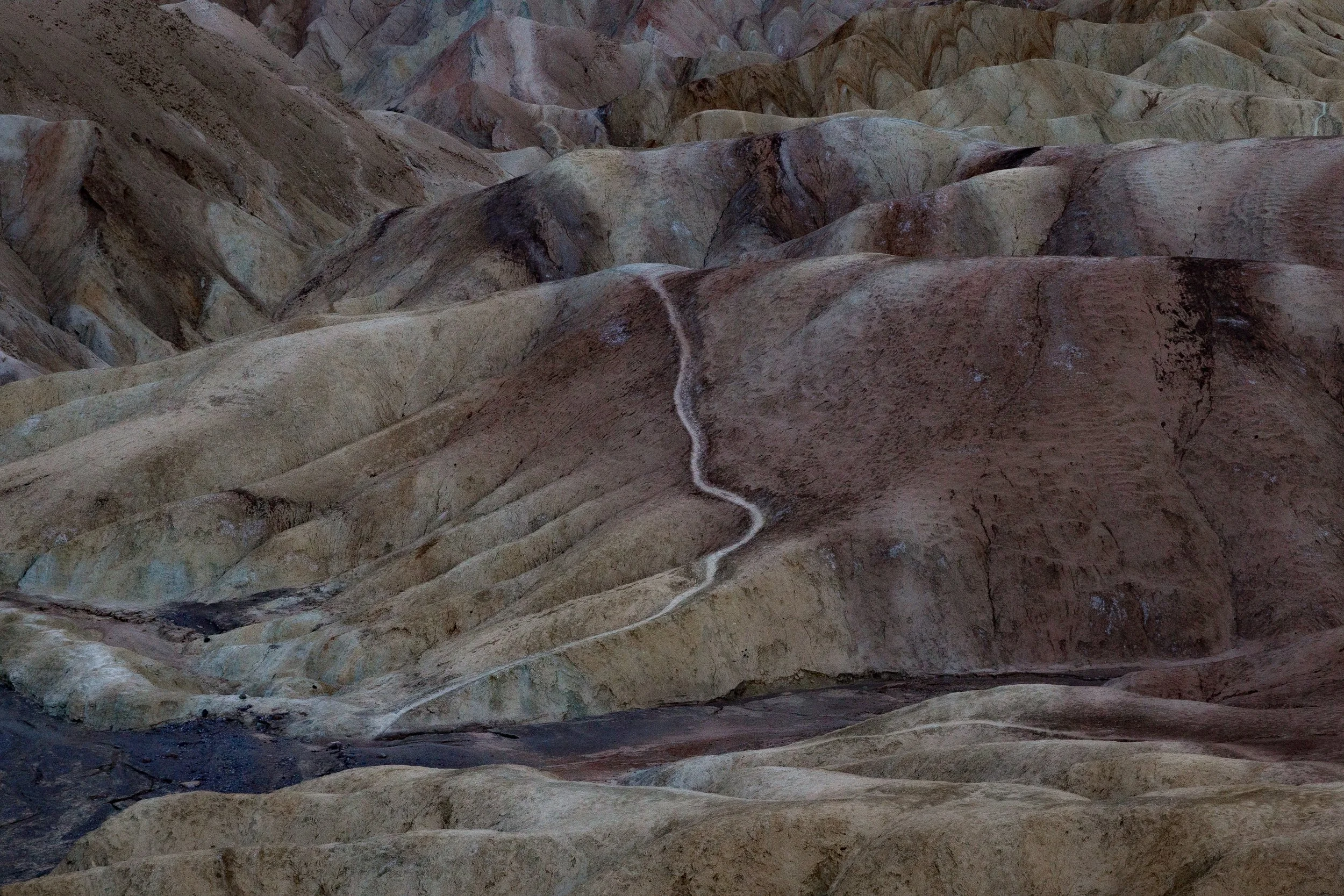 Close-up of a colorful, textured hillside with layers of sedimentary rock formations.