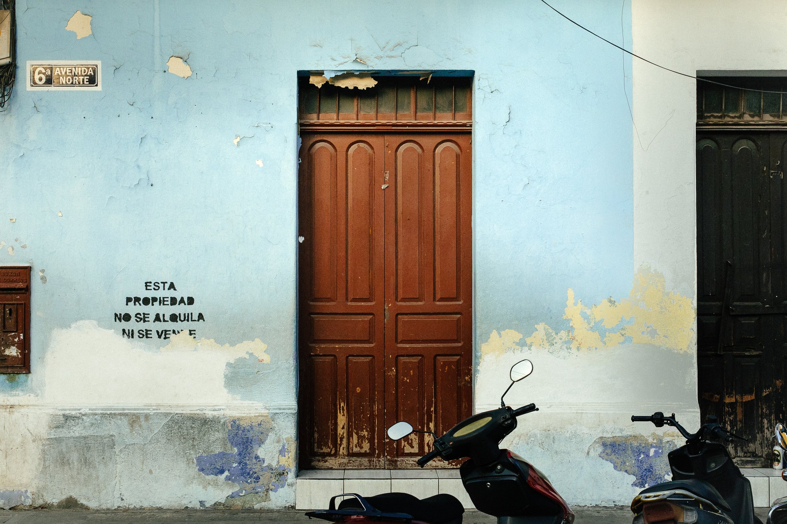 A worn, blue wall with peeling paint, a small sign indicating 