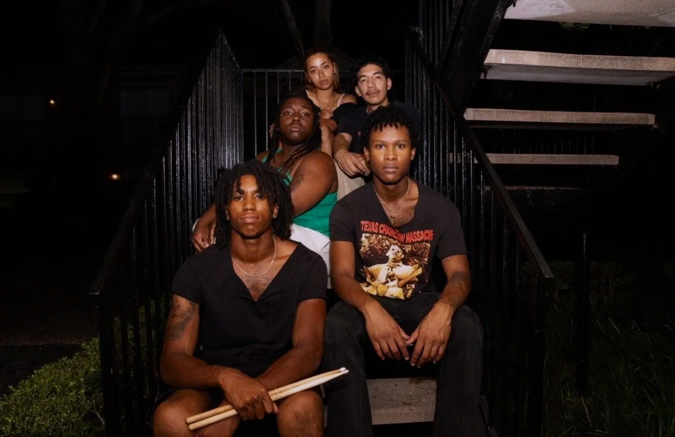 Five people sitting on stairs outside at night, posing for a photo.