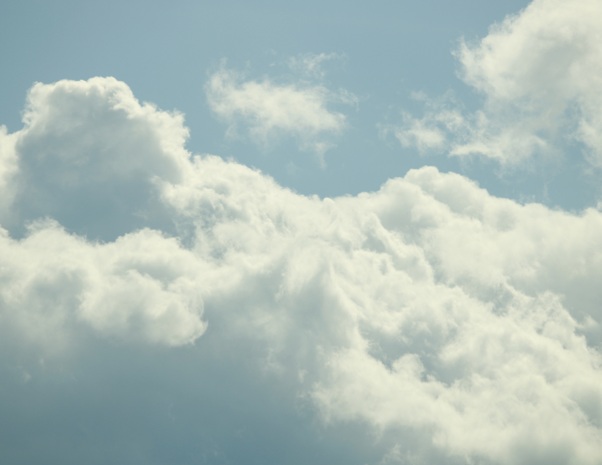 Photograph of a clear sky with scattered white clouds during daytime.
