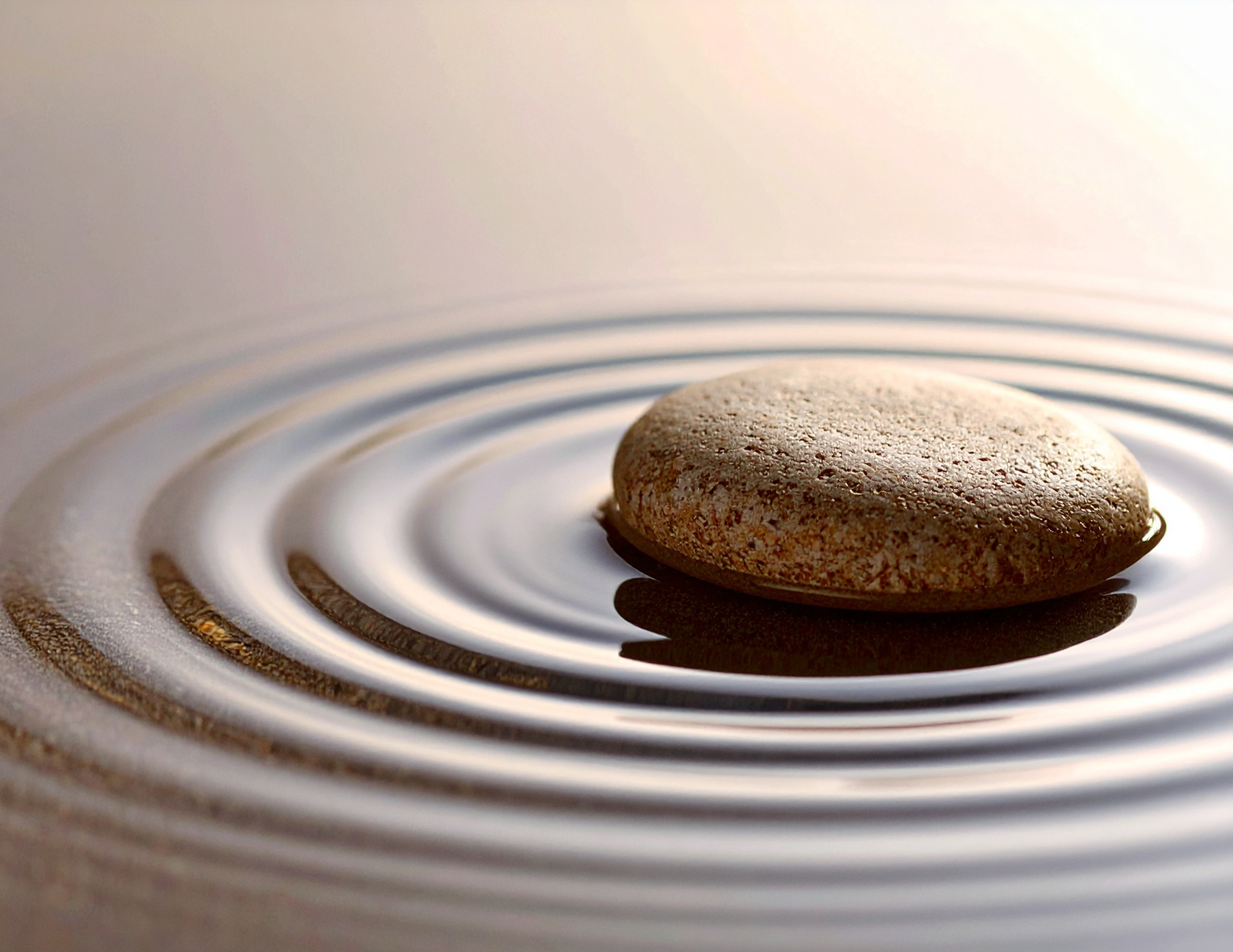 A smooth rounded pebble resting on the surface of a hot electric stove burner, which is turned on and humming, with concentric circles of heating elements visible.
