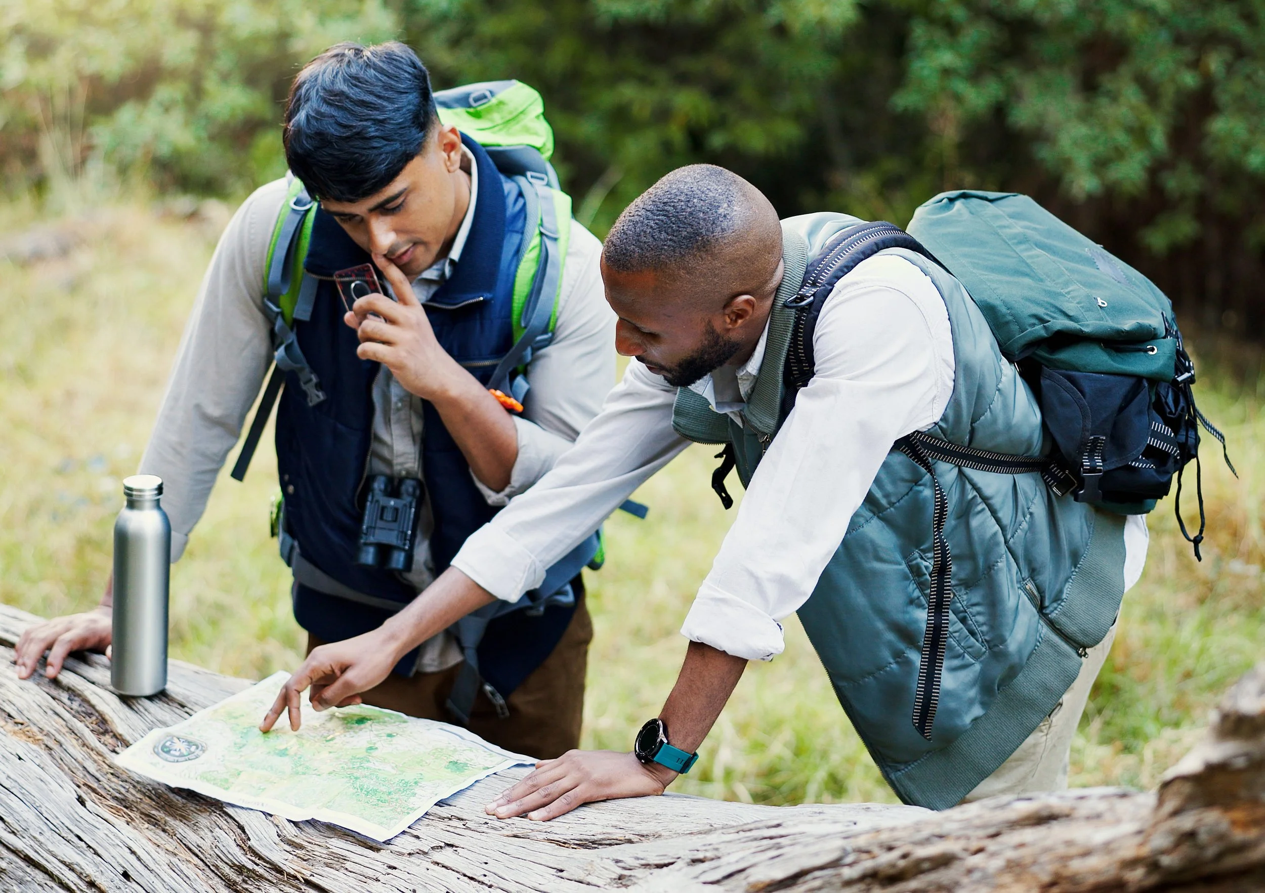 Two young hikers reviewing a trail map together outdoors.