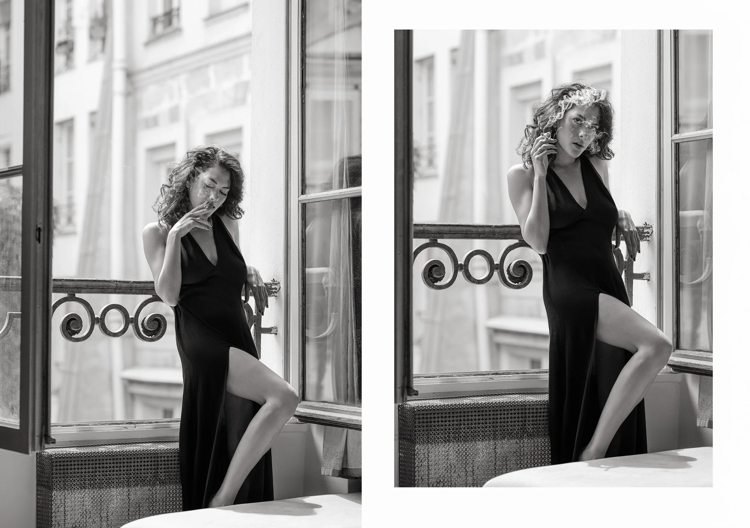 A woman in a black dress with curly hair standing by a window, smoking a cigarette, with a small balcony railing visible outside the window.