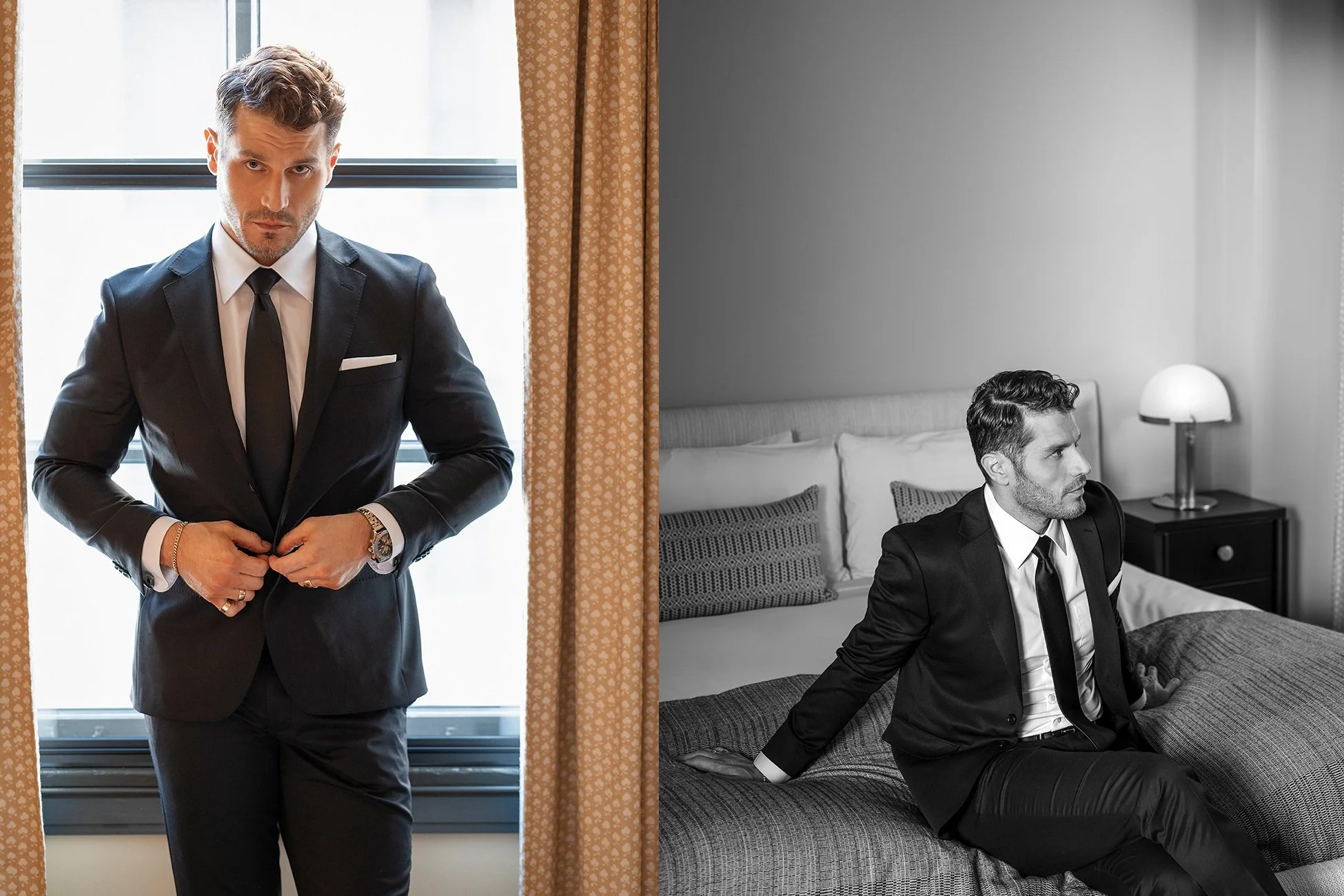 A man wearing a black suit, white shirt, and black tie, with styled hair, sitting on a bed in a hotel room, with a lamp and pillows behind him. Another similar man is standing near a window, adjusting his suit.