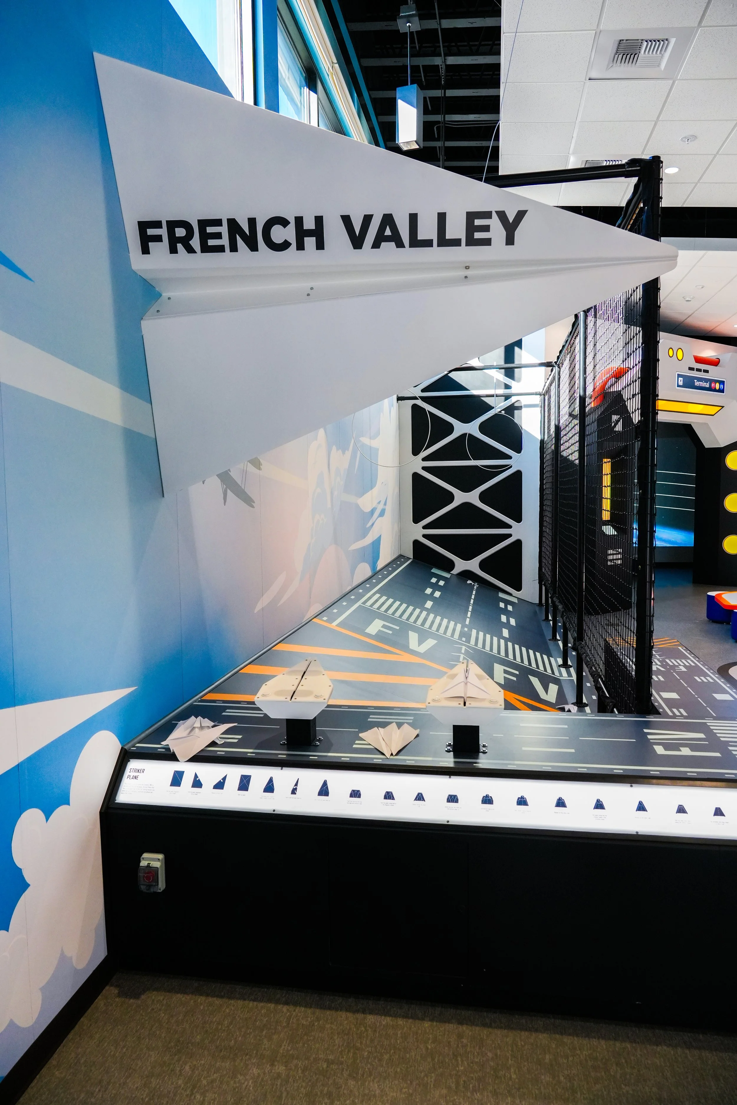 A display area with a large sign that says 'FRENCH VALLEY', showcasing model aircraft planes and components in an indoor setting, possibly a museum or aviation exhibit.