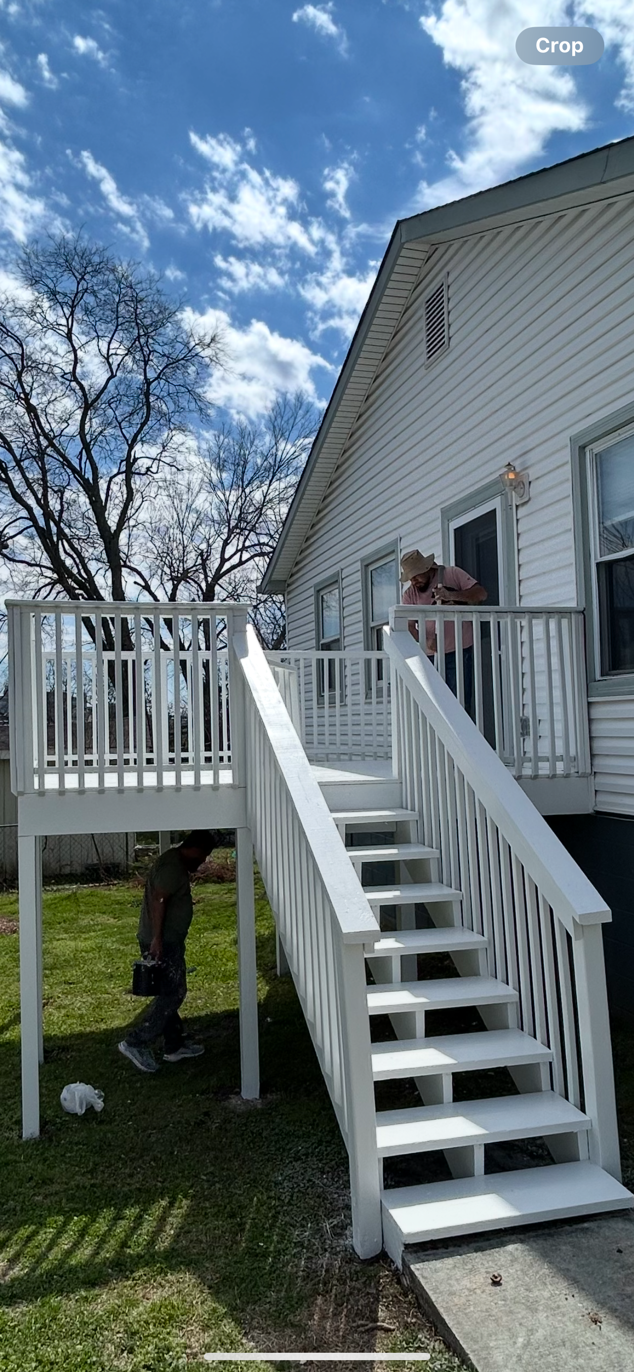 Father-and-son painting team applying a fresh white protective coating to a residential wooden deck and exterior staircase in Downtown Nashville