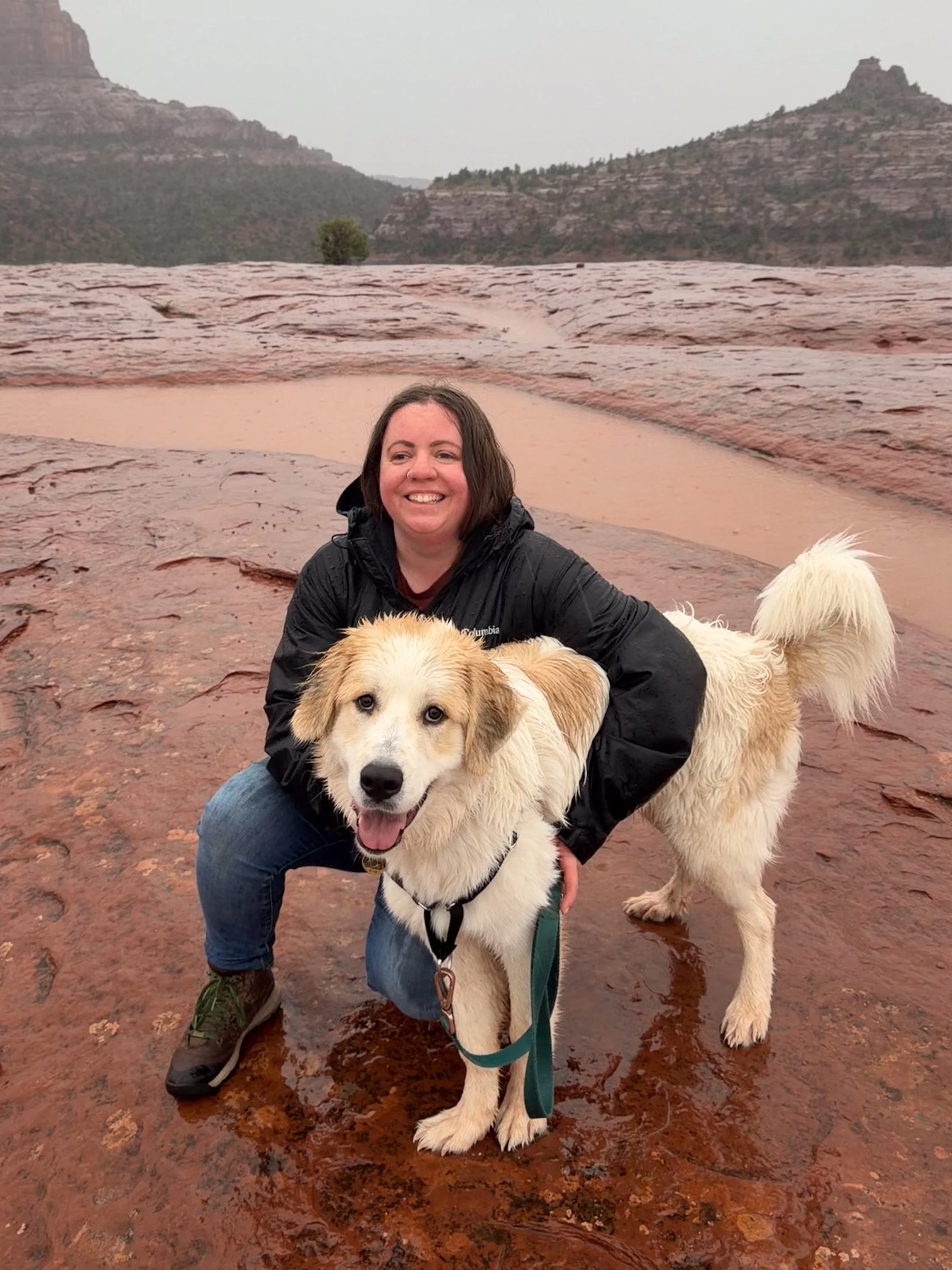 A woman smiling while hugging a great pyrenees in sedona