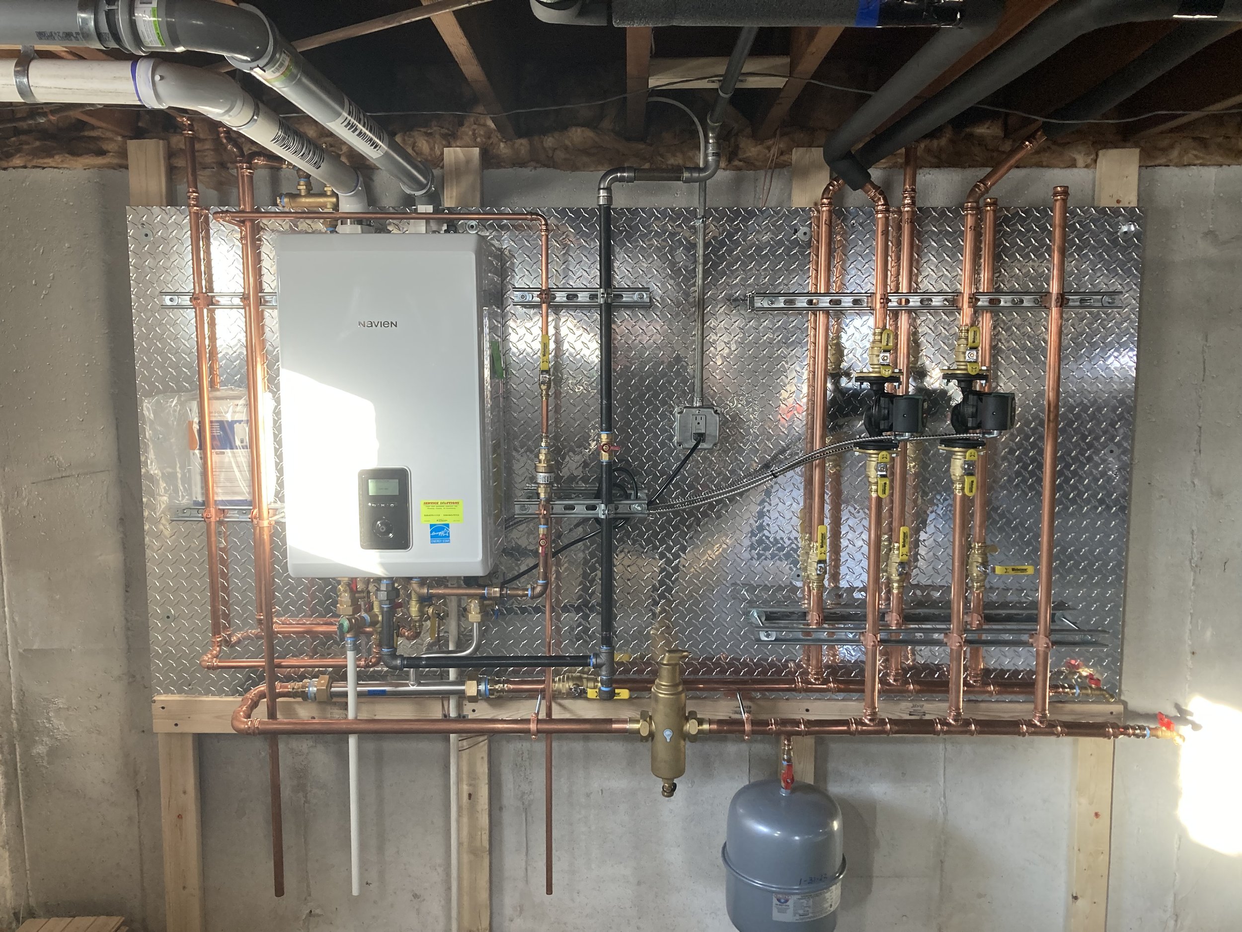 Service Solutions Plumbing Navien boiler installation with copper piping and heating zones in Massachusetts