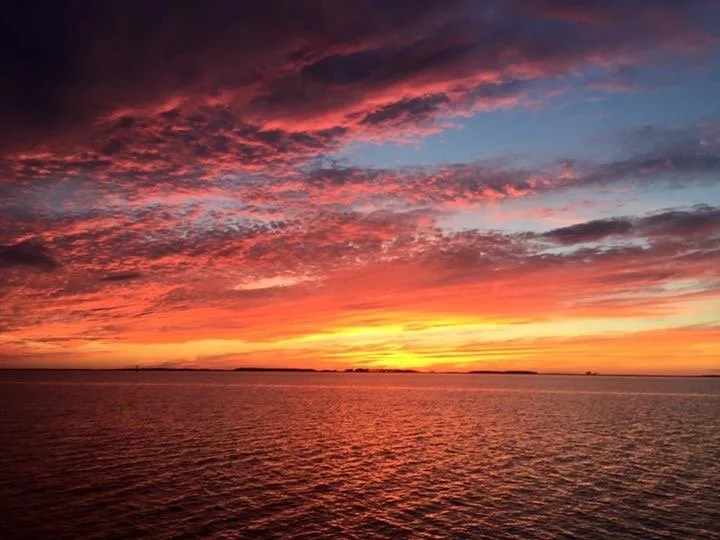 Sunset over a body of water with colorful clouds in hues of pink, orange, and purple. Chesapeake Bay, Eastern Shore of Maryland