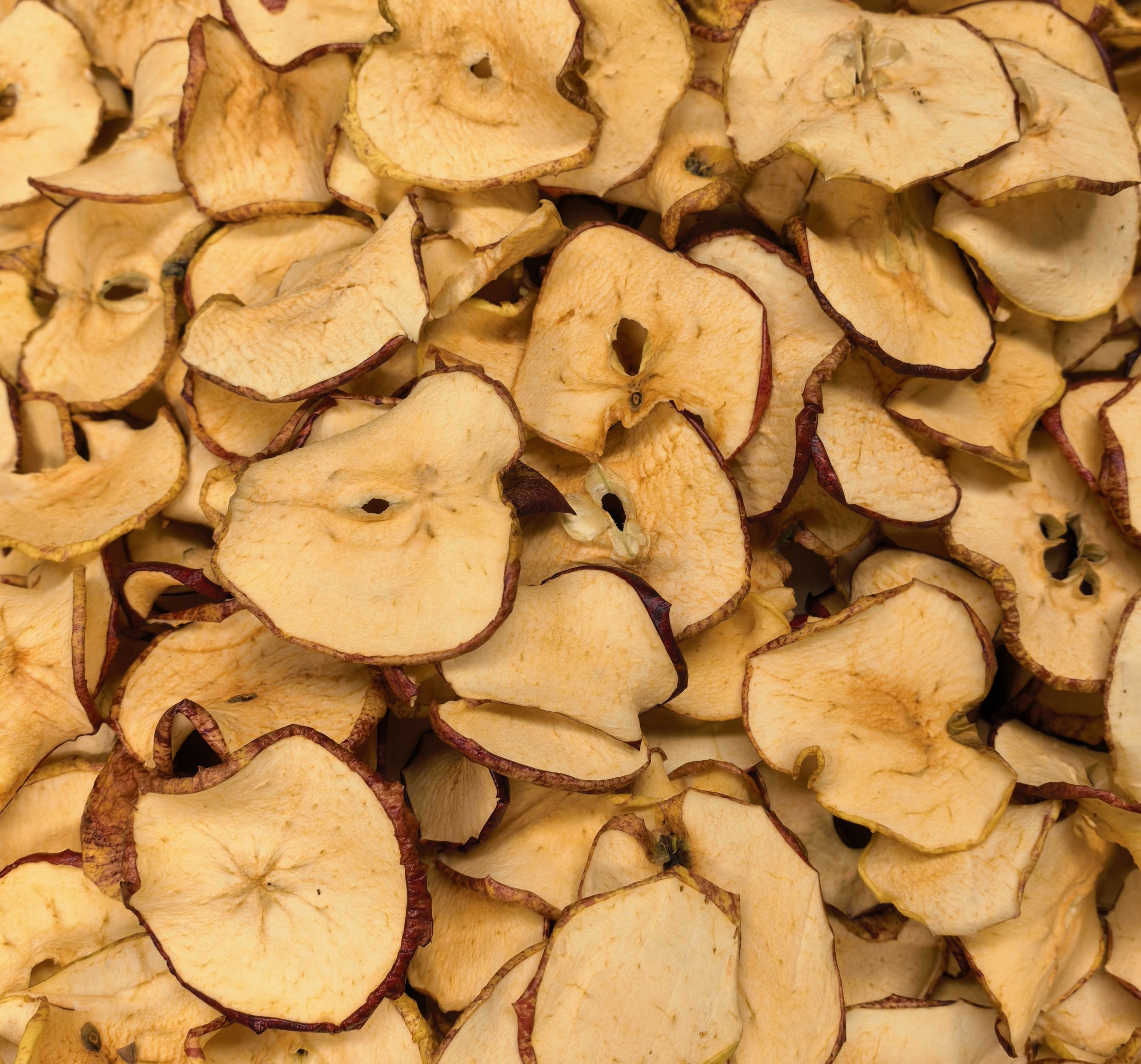 Close-up of dried apple slices with brown edges, overlapping each other.