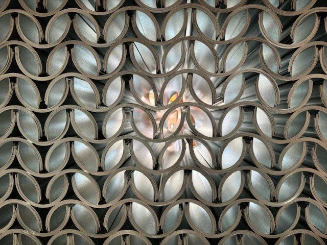 Galvanized Shields. A pattern of stacked metal shields, viewed from the front with circular openings forming a grid.