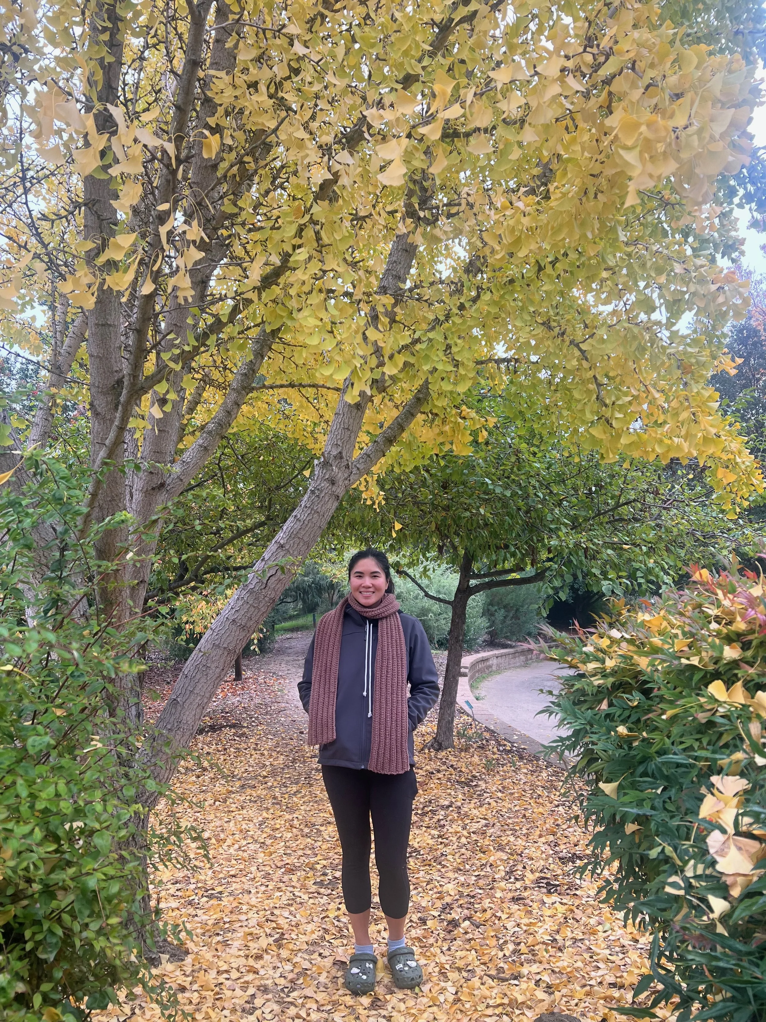 Christina Dinh smiling on a tree-lined path in a park.