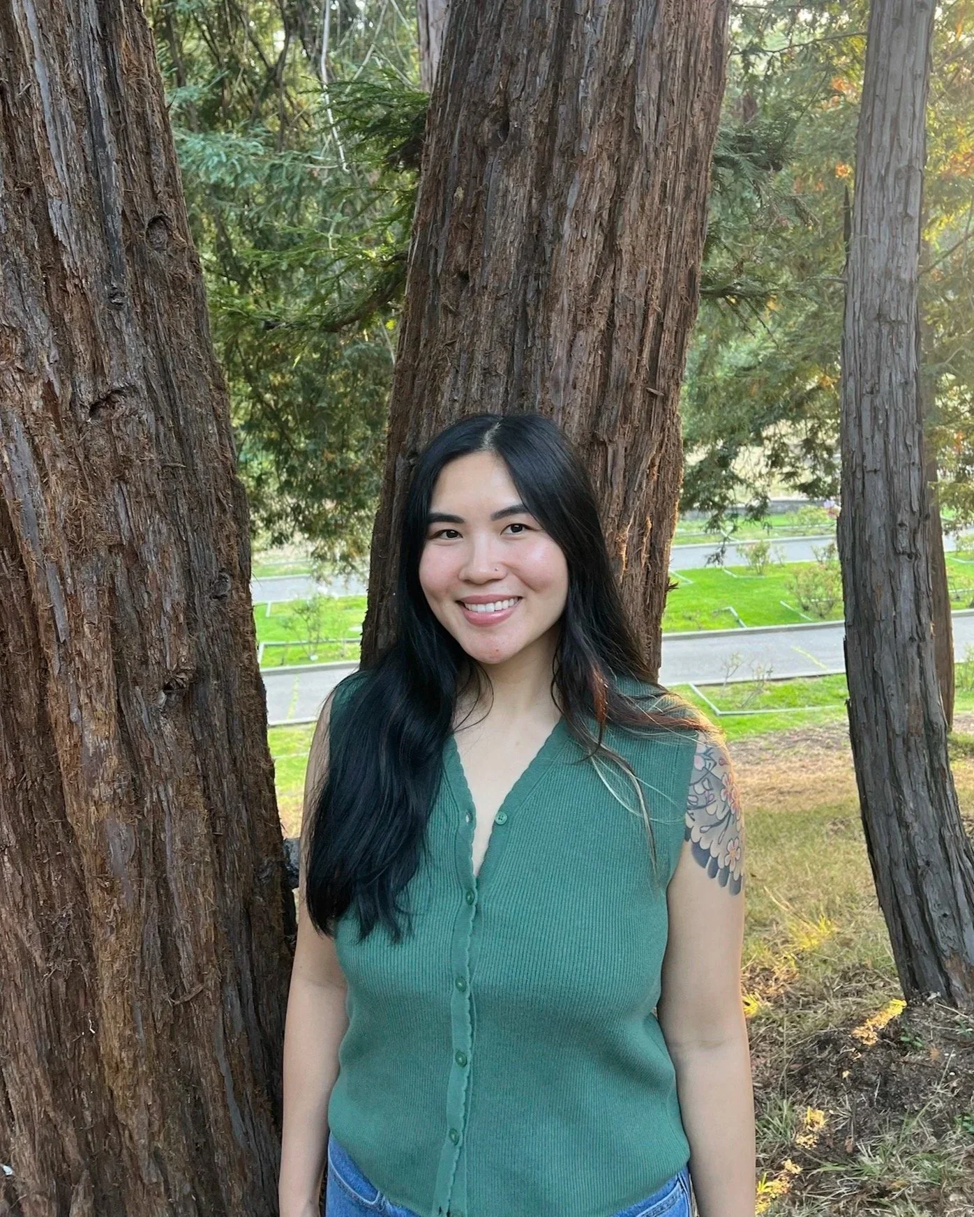 Christina Dinh smiling outdoors among trees and greenery.