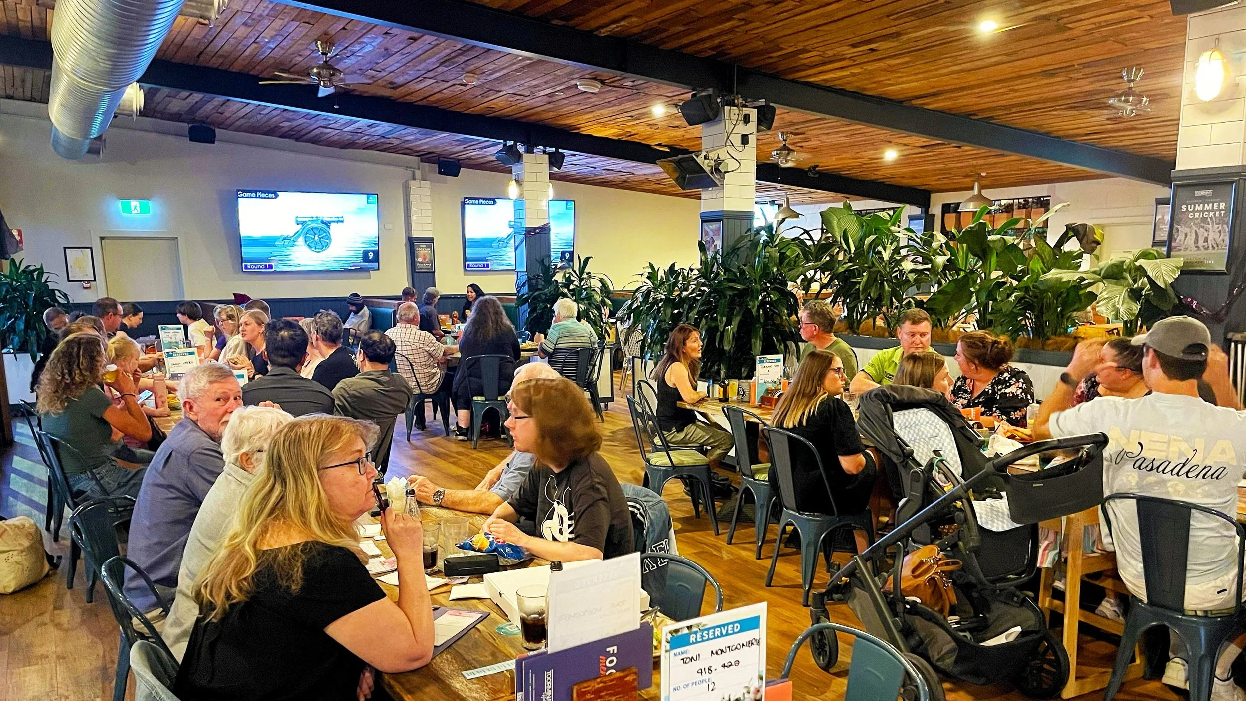 Friends socialising at a lively hospitality venue with a stage and projection screen