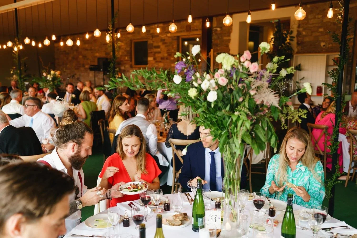Guests celebrating at an elegant wedding reception with candlelit tables and floral decorations