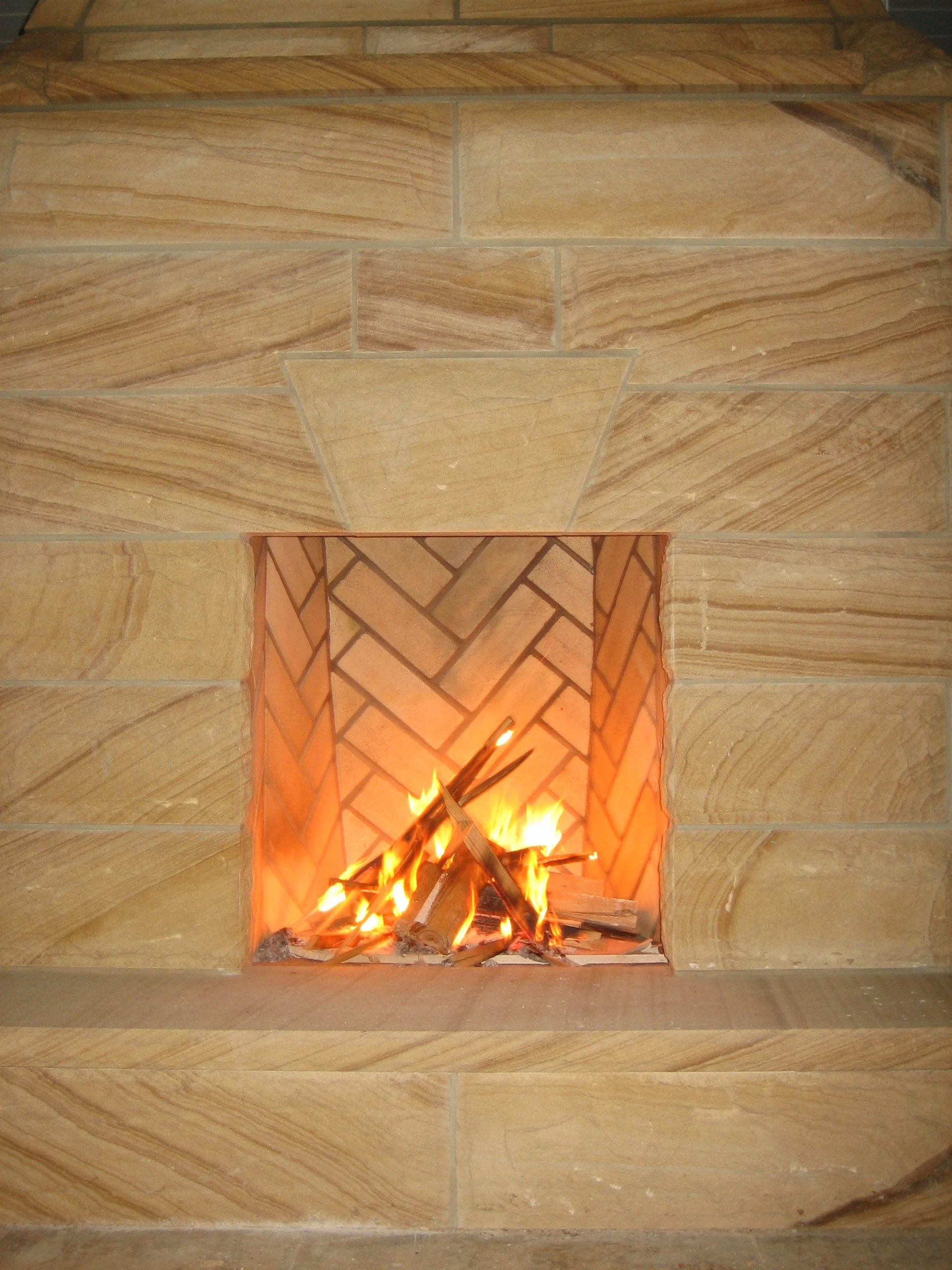 Fire burning in a built-in fireplace with a decorative brick hearth and a brick wall surround.