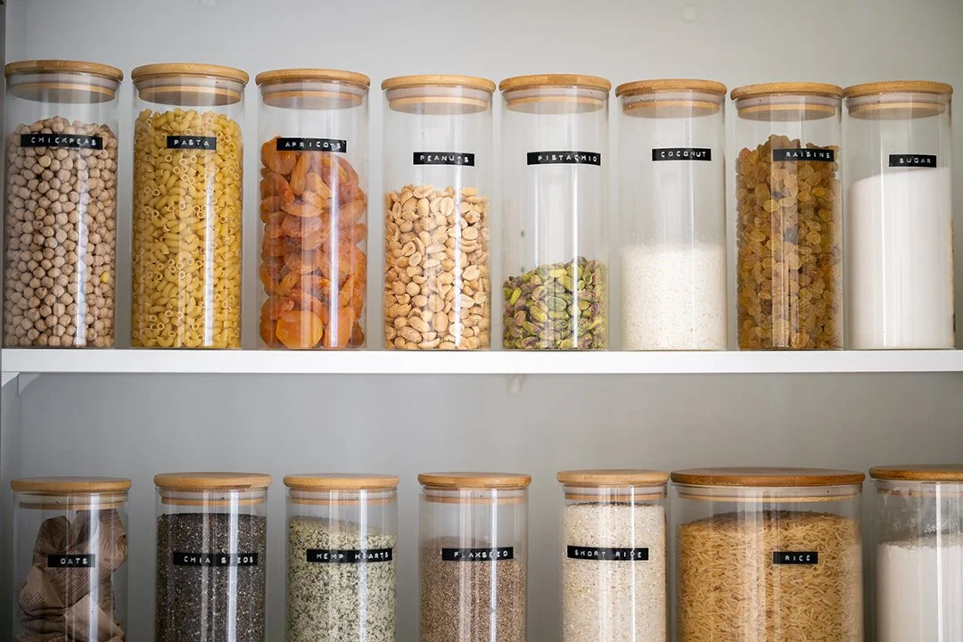 organized pantry with labeled glass jars on white shelving